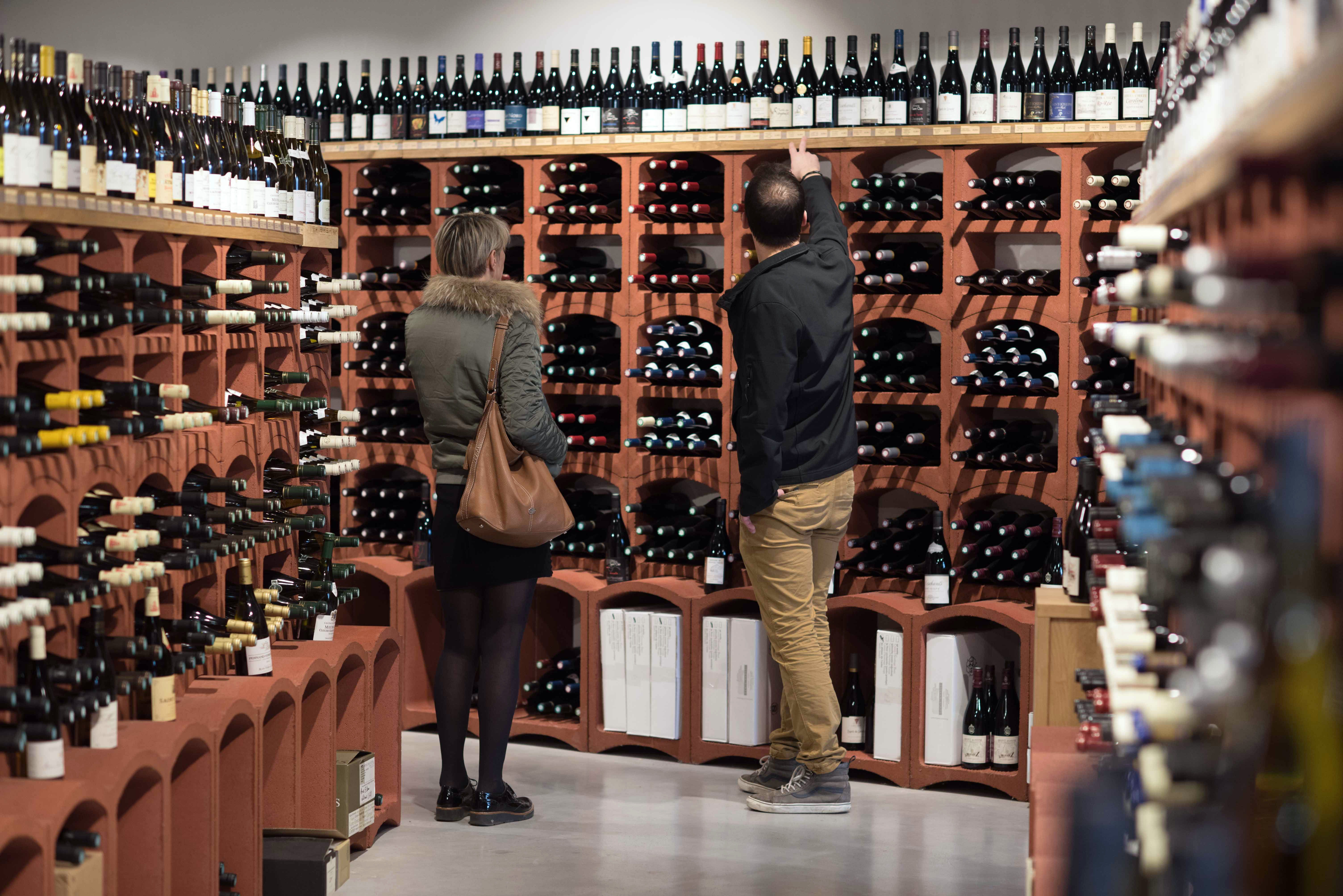 Wine racks in a wine shop: ÒAux cinq sensÓ, in Tain-l'Hermitage (south-eastern France), selling wines and spirits. Wine merchant advising a customer, a woman (Photo by: Andia/Universal Images Group via Getty Images)