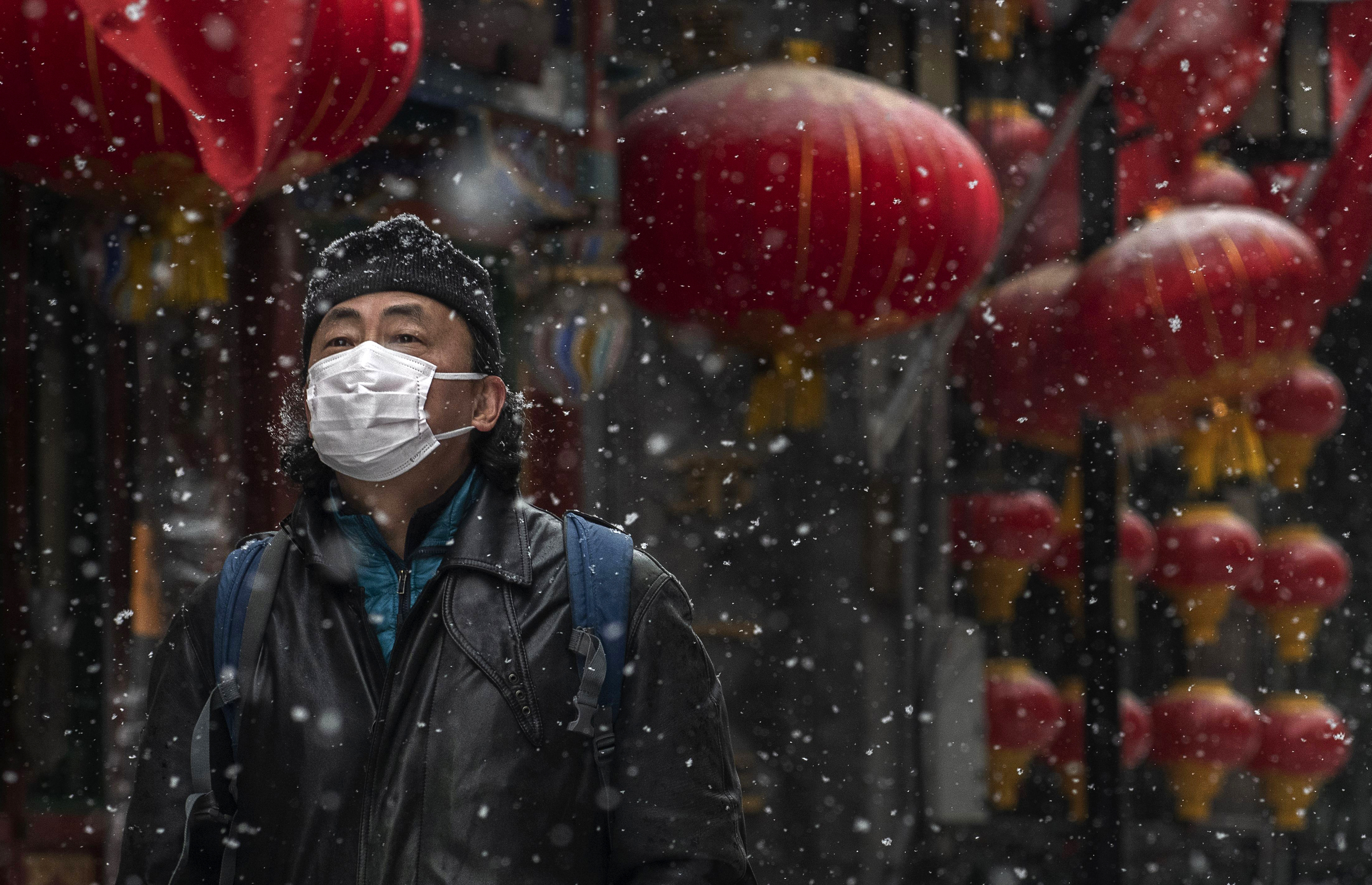 BEIJING, CHINA - FEBRUARY 05: A Chinese man wears a protective mask as he walks during a snowfall in an empty and shuttered commercial street on February 5, 2020 in Beijing, China. China's stock markets tumbled in trading on Monday, the first day back after an extended Lunar New Year holiday as a mystery virus continues to spread in China and worldwide. The number of cases of a deadly new coronavirus rose to more than 20000 in mainland China Wednesday, days after the World Health Organization (WHO) declared the outbreak a global public health emergency. China continued to lock down the city of Wuhan in an effort to contain the spread of the pneumonia-like disease which medicals experts have confirmed can be passed from human to human. In an unprecedented move, Chinese authorities have put travel restrictions on the city which is the epicentre of the virus and neighbouring municipalities affecting tens of millions of people. The number of those who have died from the virus in China climbed to over 490 on Thursday, mostly in Hubei province, and cases have been reported in other countries including the United States, Canada, Australia, Japan, South Korea, India, the United Kingdom, Germany, France and several others. The World Health Organization has warned all governments to be on alert and screening has been stepped up at airports around the world. Some countries, including the United States, have put restrictions on Chinese travellers entering and advised their citizens against travel to China. (Photo by Kevin Frayer/Getty Images)
