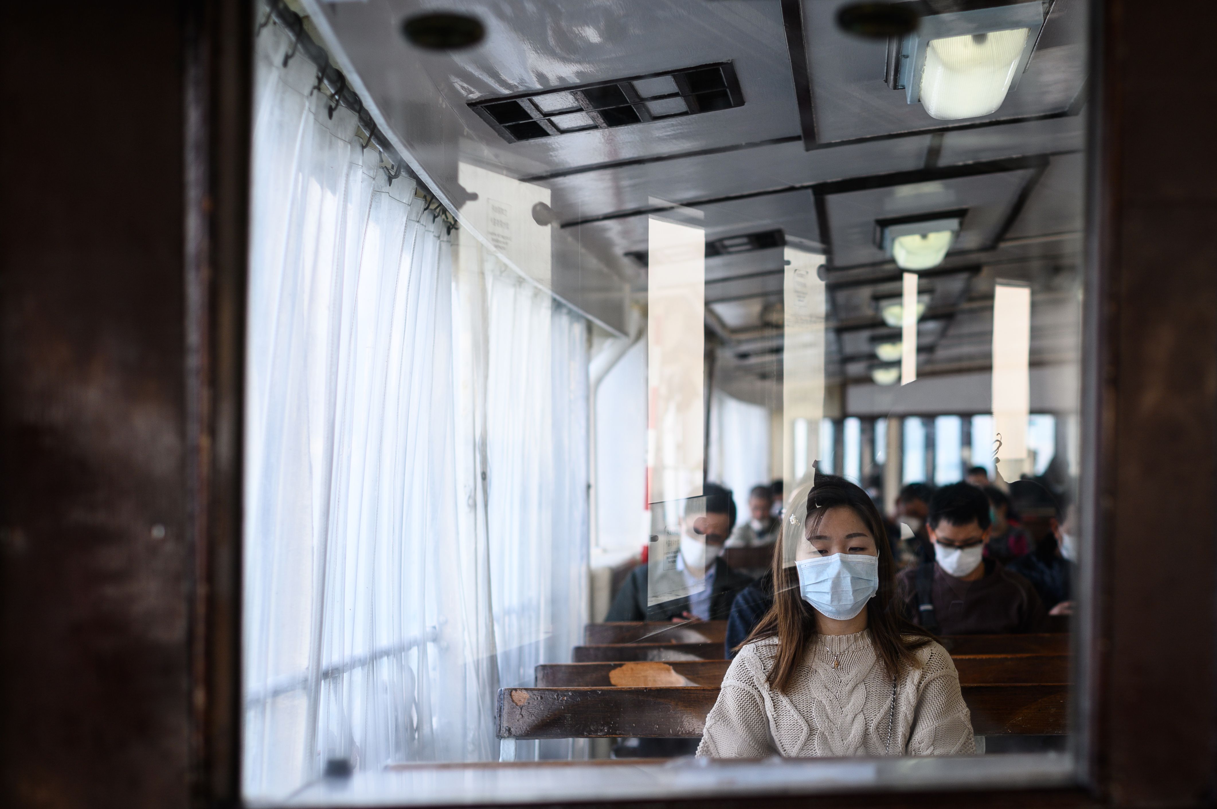 Passengers wear face masks, as a preventative measure against the COVID-19 coronavirus, as they travel on a ferry from Hong Kong island to Koloon side of Hong Kong on February 12, 2020. - The death toll from the COVID-19 coronavirus epidemic climbed past 1,100 on February 12 but the number of new cases fell for a second straight day, raising hope the outbreak could peak later this month. (Photo by Philip FONG / AFP) (Photo by PHILIP FONG/AFP via Getty Images)