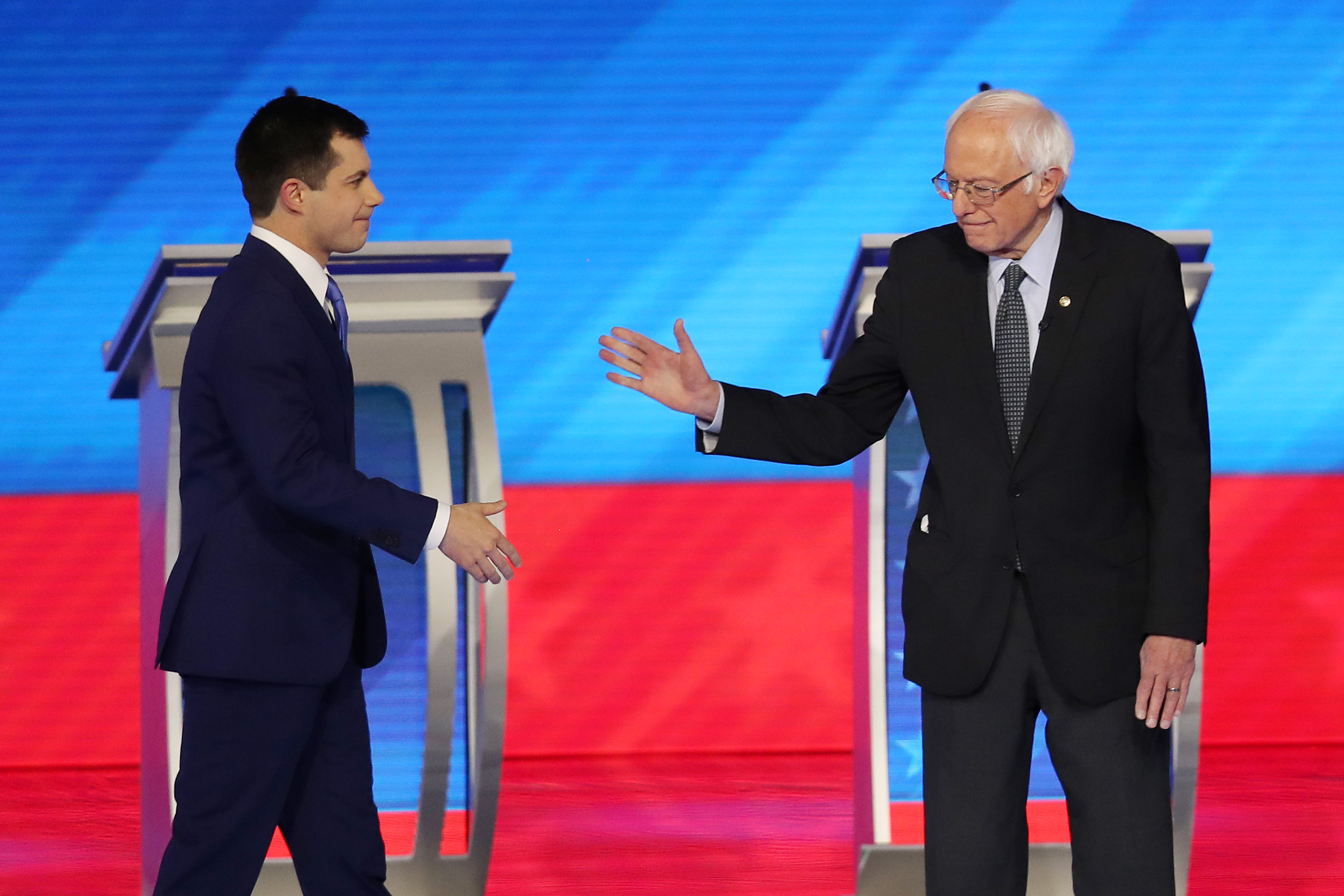 (L-R) Democratic presidential candidates former South Bend, Indiana Mayor Pete Buttigieg and Sen. Bernie Sanders (I-VT) greet each other prior to the start of the Democratic presidential primary debate in the Sullivan Arena at St. Anselm College on February 07, 2020 in Manchester, New Hampshire. 