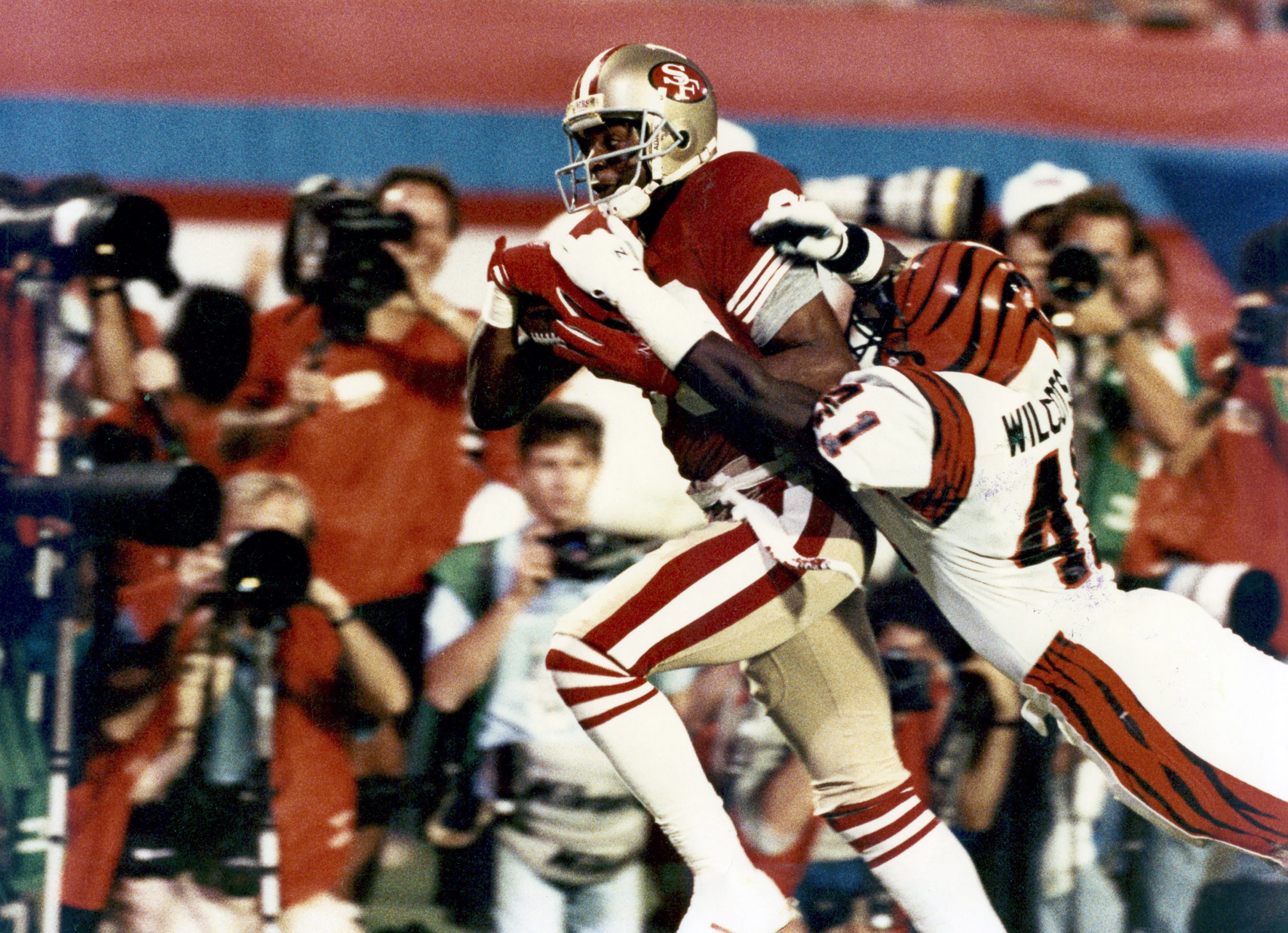 San Francisco 49ers wide receiver Jerry Rice (80) runs with the football after making a catch and drags Bengals defensive back Solomon Wilcots (41) along the way during the 4th quarter of the 49ers 20-16 victory over the Cincinnati Bengals in Super Bowl XXIII on January 22, 1989.