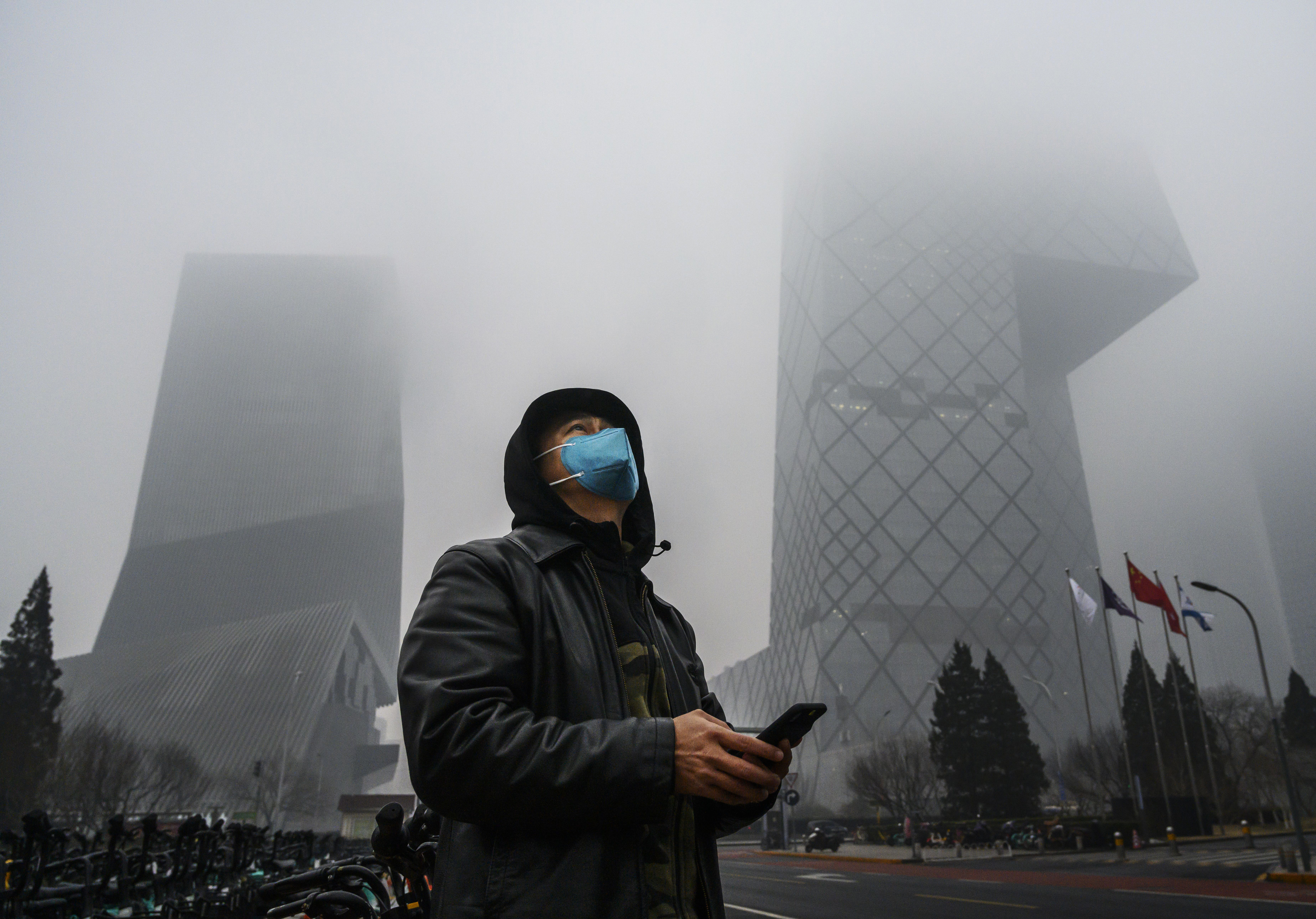 BEIJING, CHINA - FEBRUARY 13: A Chinese man wears a protective mask as he stands near the CCTV building in fog and pollution during rush hour in the central business district on February 13, 2020 in Beijing, China. The number of cases of the deadly new coronavirus COVID-19 rose to more than 52000 in mainland China Thursday, in what the World Health Organization (WHO) has declared a global public health emergency. China continued to lock down the city of Wuhan in an effort to contain the spread of the pneumonia-like disease which medicals experts have confirmed can be passed from human to human. In an unprecedented move, Chinese authorities have maintained and in some cases tightened the travel restrictions on the city which is the epicentre of the virus and also in municipalities in other parts of the country affecting tens of millions of people. The number of those who have died from the virus in China climbed to over 1300 on Thursday, mostly in Hubei province, and cases have been reported in other countries including the United States, Canada, Australia, Japan, South Korea, India, the United Kingdom, Germany, France and several others. The World Health Organization has warned all governments to be on alert and screening has been stepped up at airports around the world. Some countries, including the United States, have put restrictions on Chinese travellers entering and advised their citizens against travel to China. (Photo by Kevin Frayer/Getty Images)
