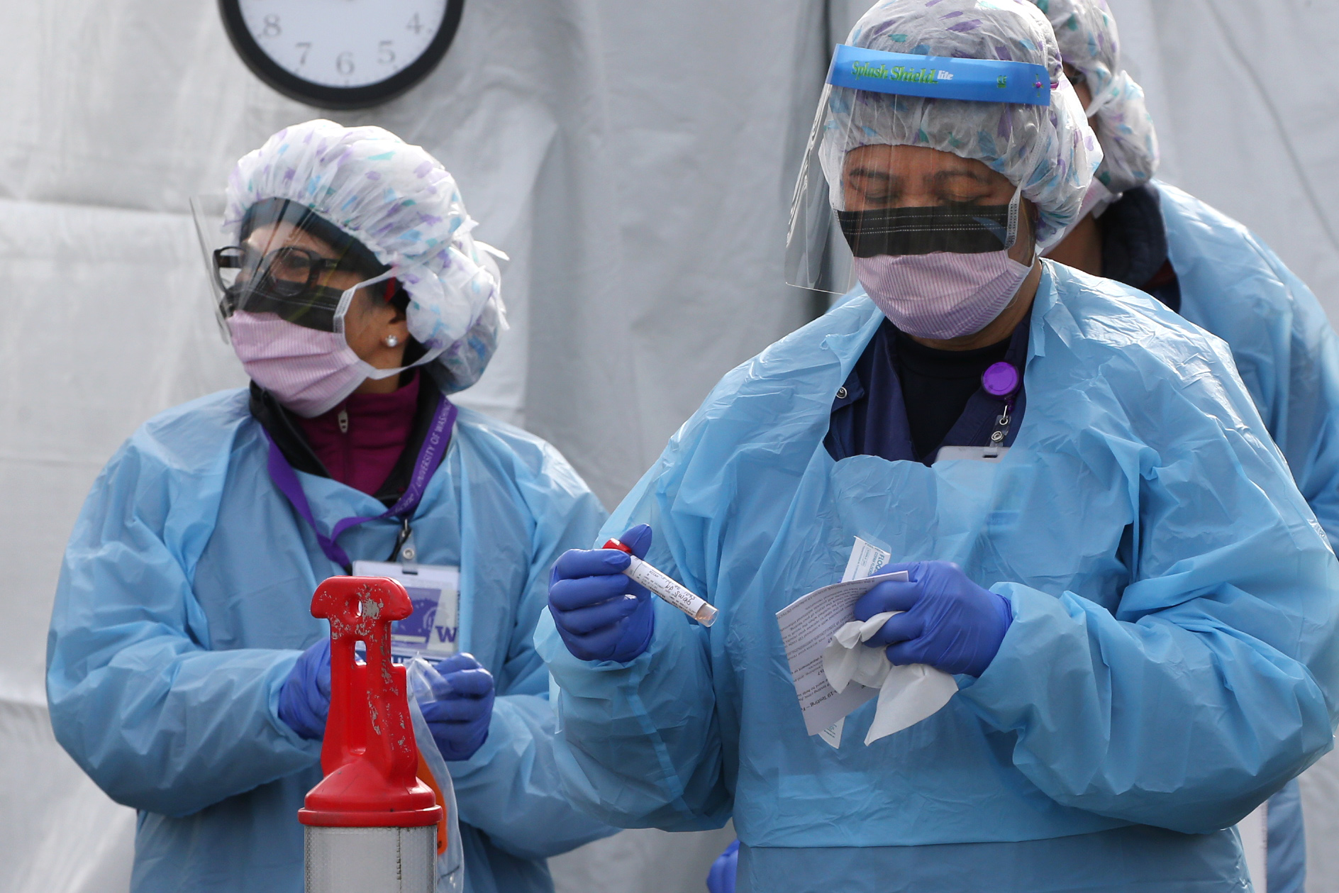 SEATTLE, WA - MARCH 17:  Nurses process a sample for  COVID-19 after a patient was screened at an appointment-only, drive-up clinic set up by the University of Washington Medical Center  Northwest Outpatient Medical Center on March 17, 2020 in Seattle, Washington. The clinic was set up to provide additional screening capacity, support personal protective equipment conservation efforts and help reduce the number of patients entering healthcare facilities for testing during the coronavirus outbreak. 