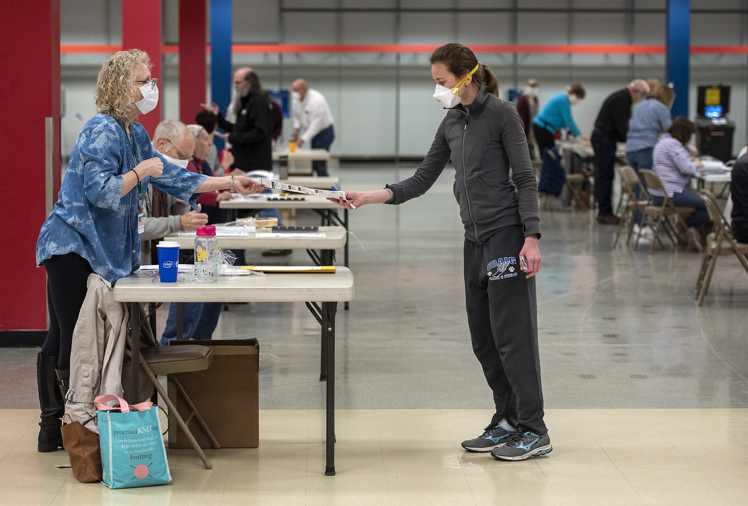 Bridget McDonald, right, receives a ballot from poll worker Patty Piek-Groth on Tuesday, April 7, 2020, at the Janesville Mall in Janesville, Wis. Angela Major—The Janesville Gazette via AP