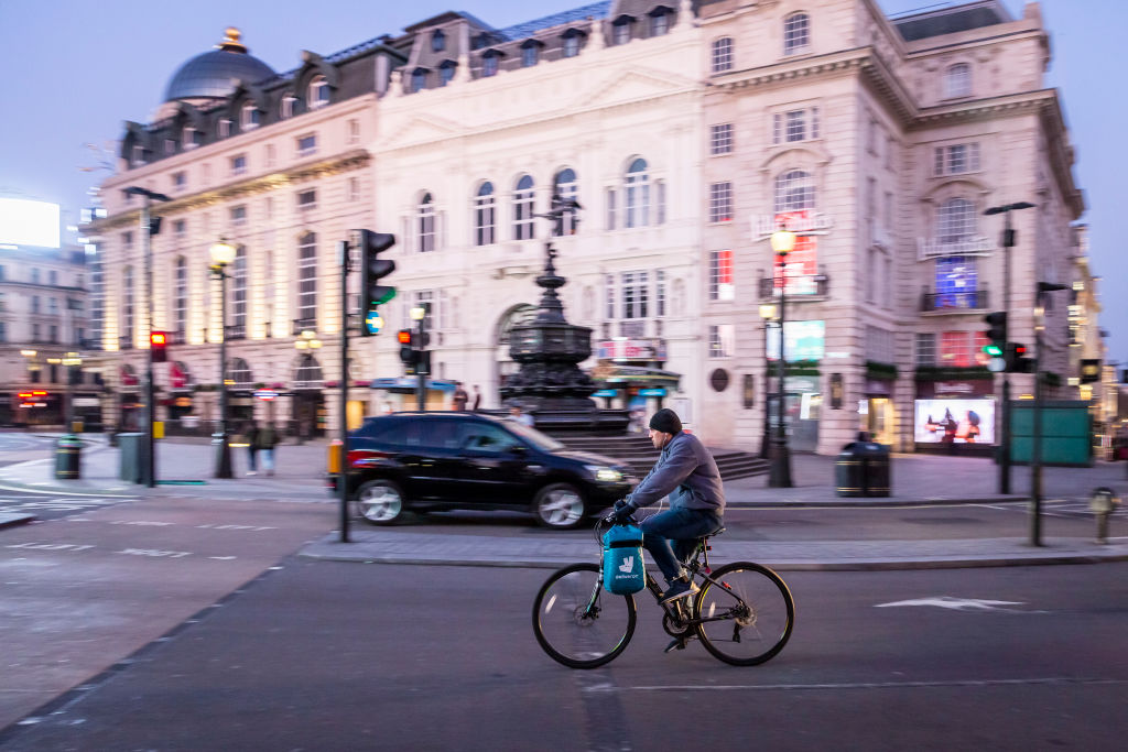 A Deliveroo delivery rider cycles through an almost deserted Picadilly Circus in London on March 27th, 2020. The centre of London is extremely quiet with almost every business closed and very few people about because of the Government's lockdown measures due to the Coronavirus crisis. Gig economy workers ssuch as delivery riders and drivers are facing financial uncertainty caused by the economic shut down. (Photo by Jonathan Perugia/In Pictures via Getty Images)