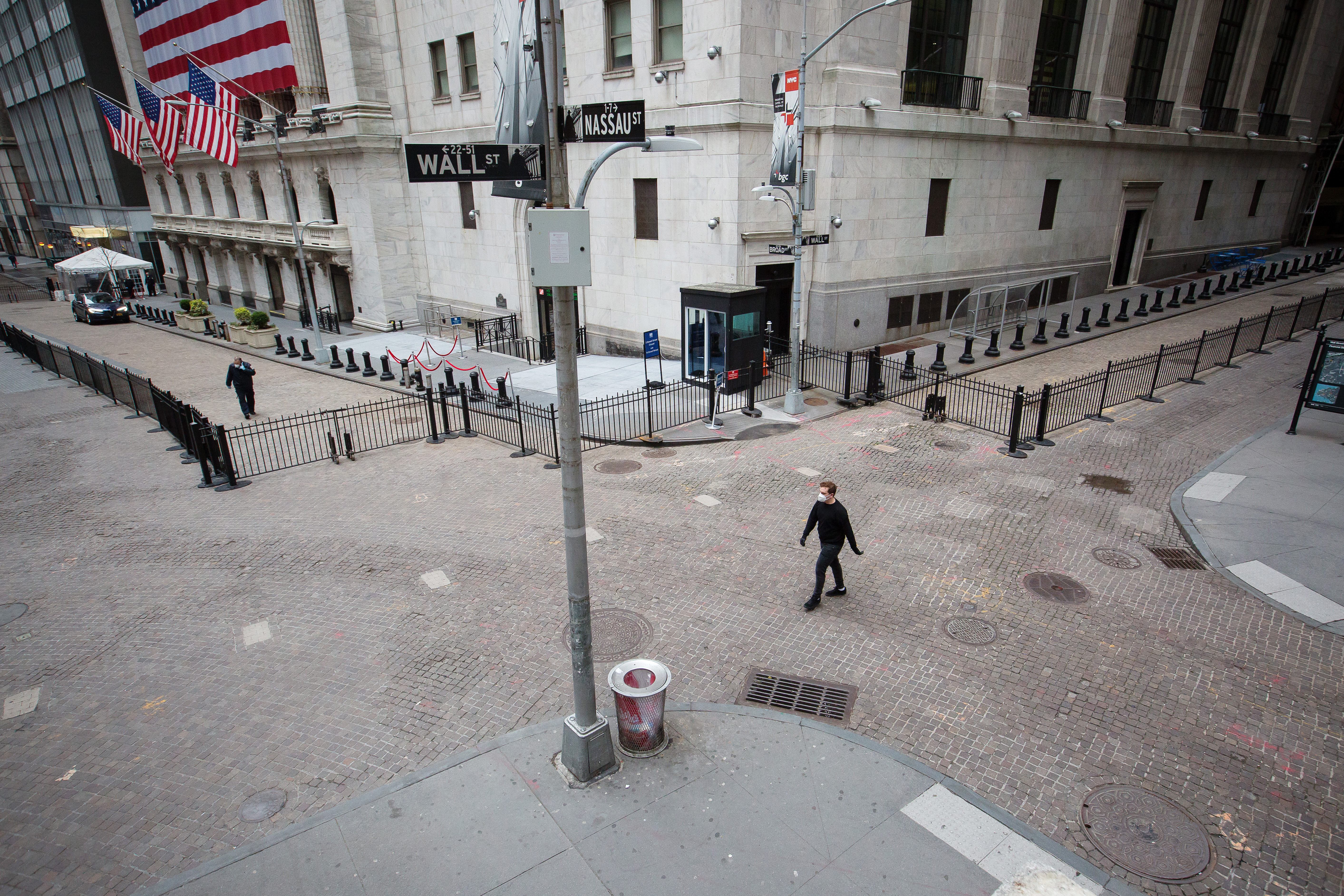 A pedestrian wearing a protective mask walks along Wall Street in front of the New York Stock Exchange (NYSE) in New York. Global shares fell in early trade on Wednesday as President Trump warned of a "painful" two weeks as the coronavirus crisis worsens in the U.S. Wire photography: Michael Nagle—Bloomberg via Getty Images