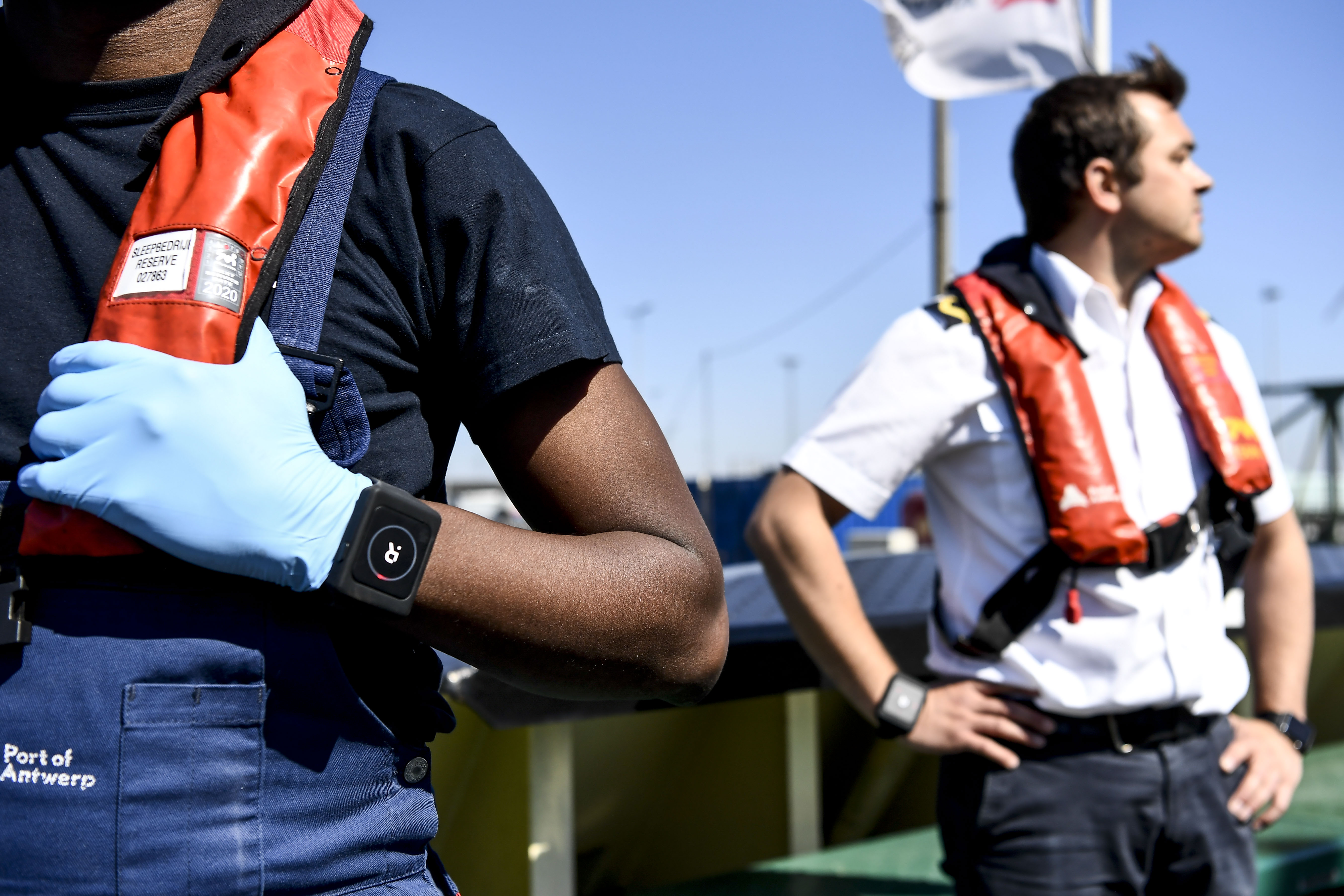 A Belgian deck hand and a captain wear a Romware Covid Radius bracelet during a presentation of the device at the Port of Antwerp, on April 22, 2020. - The bracelet, produced by a company named Rombit, usually serves to localize workers and dangers in hazardous areas and is now used to guarantee social distancing and tracing the contacts. (Photo by DIRK WAEM / BELGA / AFP) / Belgium OUT (Photo by DIRK WAEM/BELGA/AFP via Getty Images)