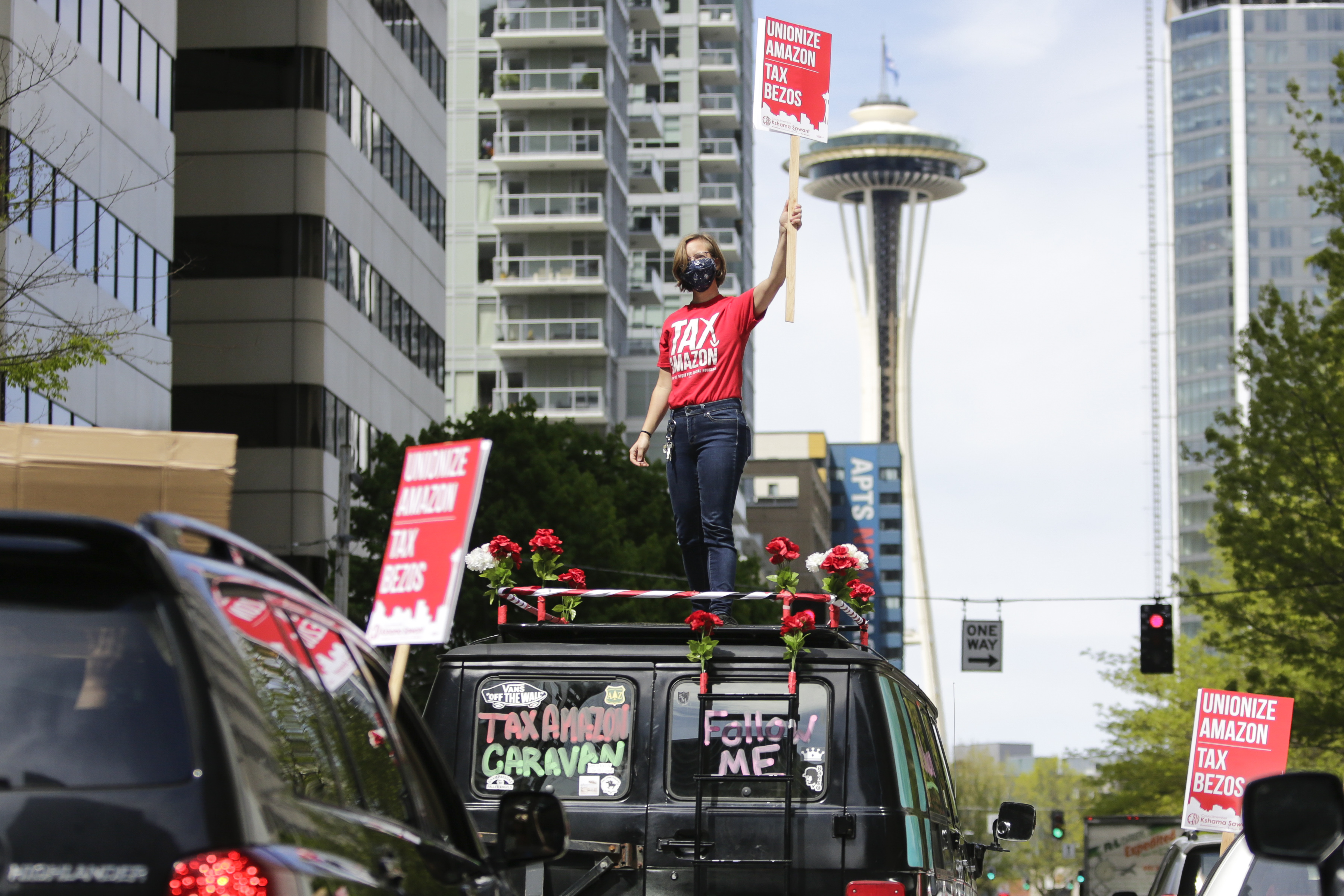 Protesters stand on their cars and block traffic as they participate in a "car caravan" protest at the Amazon Spheres to demand the Seattle City Council tax the city's largest businesses in Seattle.
