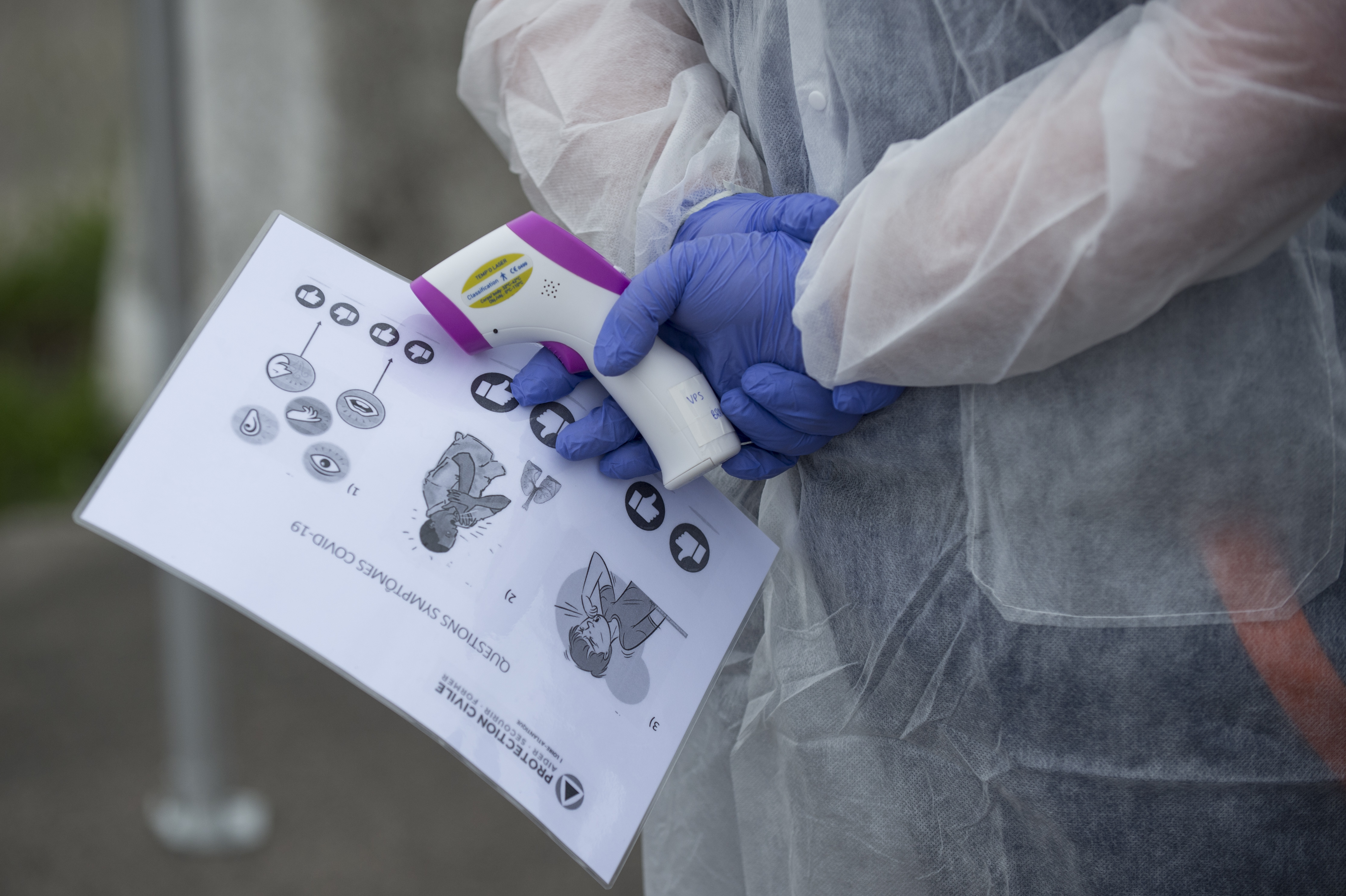 A member of the French civil protection (protection civile) holds a thermometer and a document with pictograms to ask to migrants and homeless people to verify if they have symptoms of COVID-19 coronavirus in a accommodation center in Nantes, western France, on May 08, 2020, on the 53rd day of a strict lockdown in France to attempt to stop the spread of the new coronavirus (COVID-19). (Photo by Sebastien SALOM-GOMIS / AFP) (Photo by SEBASTIEN SALOM-GOMIS/AFP via Getty Images)