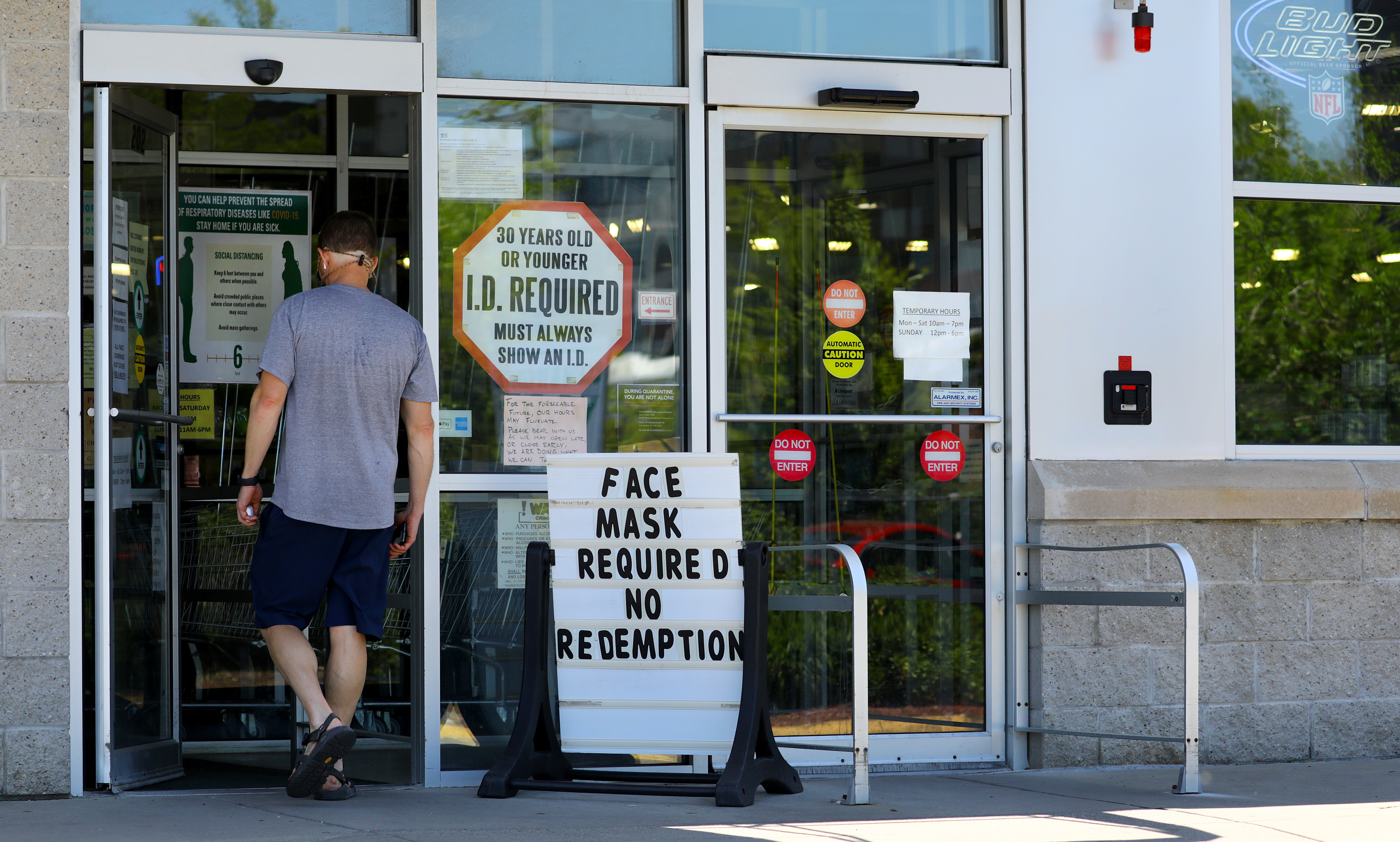 A sign outside Cambridge Wine & Spirits states that masks are required. Pat Greenhouse—The Boston Globe via Getty Images