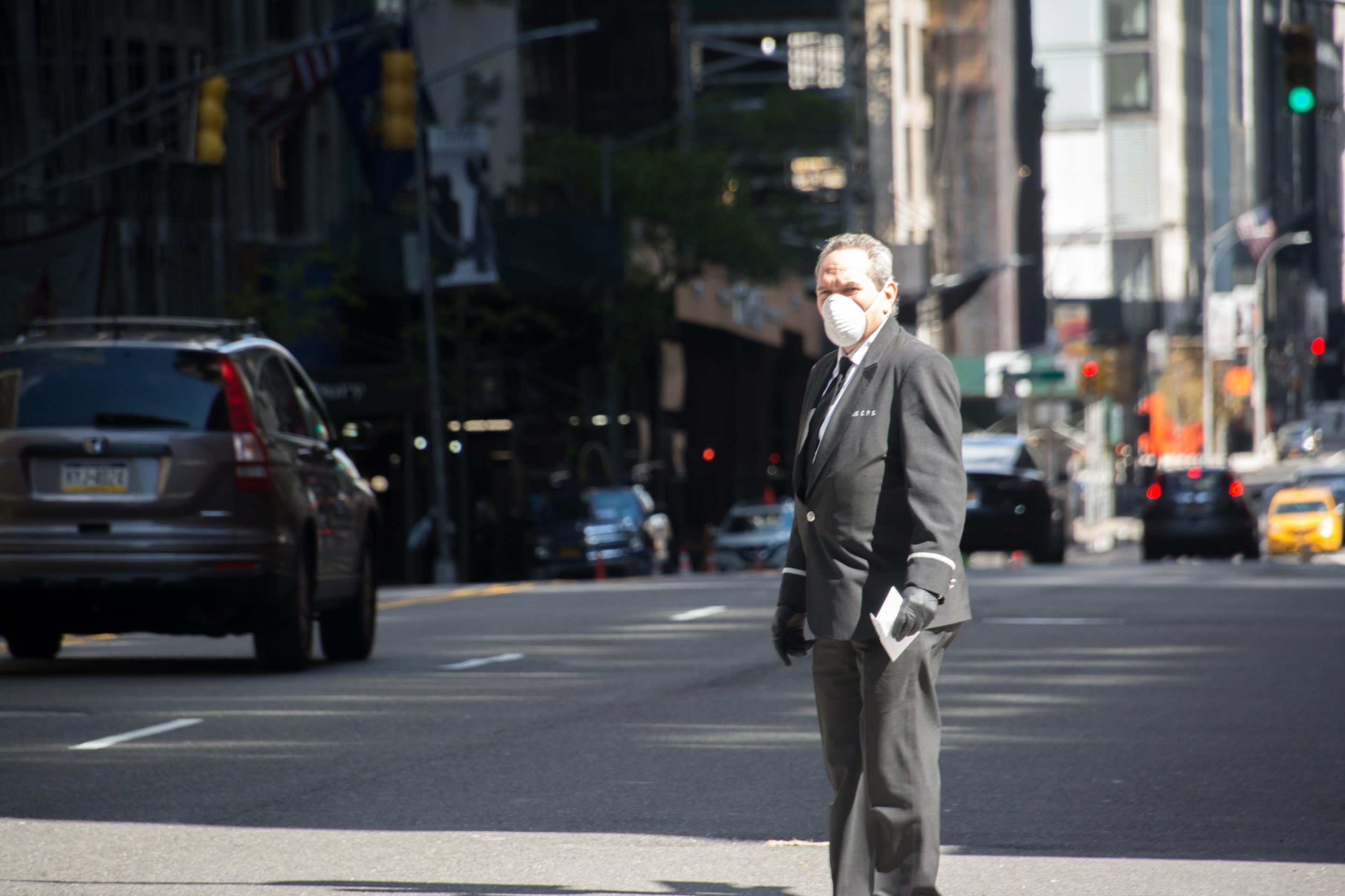New York City, United States - April 23rd, 2020: An old man with a uniform and face mask, crosses the street