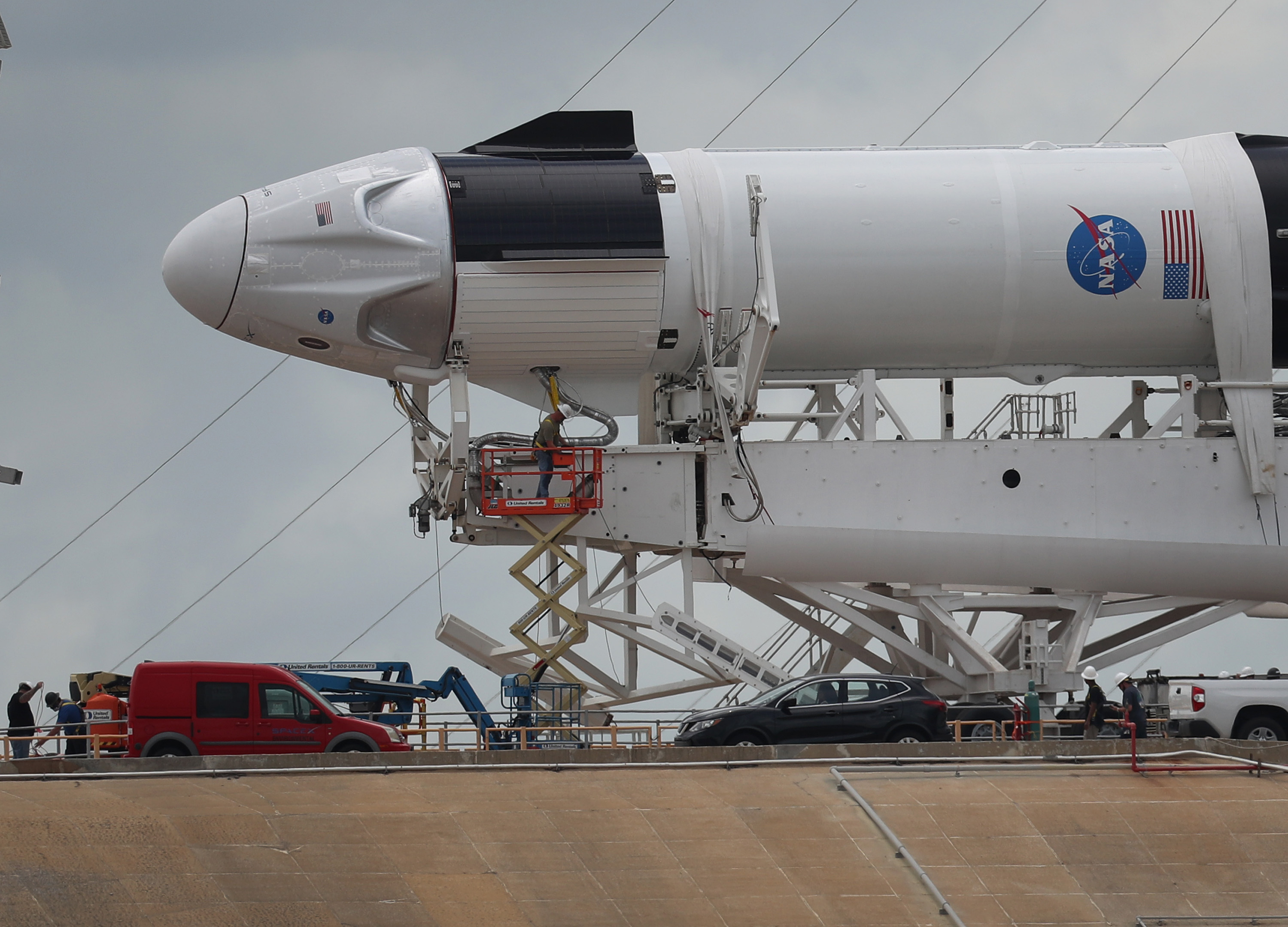 Workers prepare the SpaceX Falcon 9 rocket with the Crew Dragon spacecraft attached for the scheduled liftoff from the Kennedy Space Center.