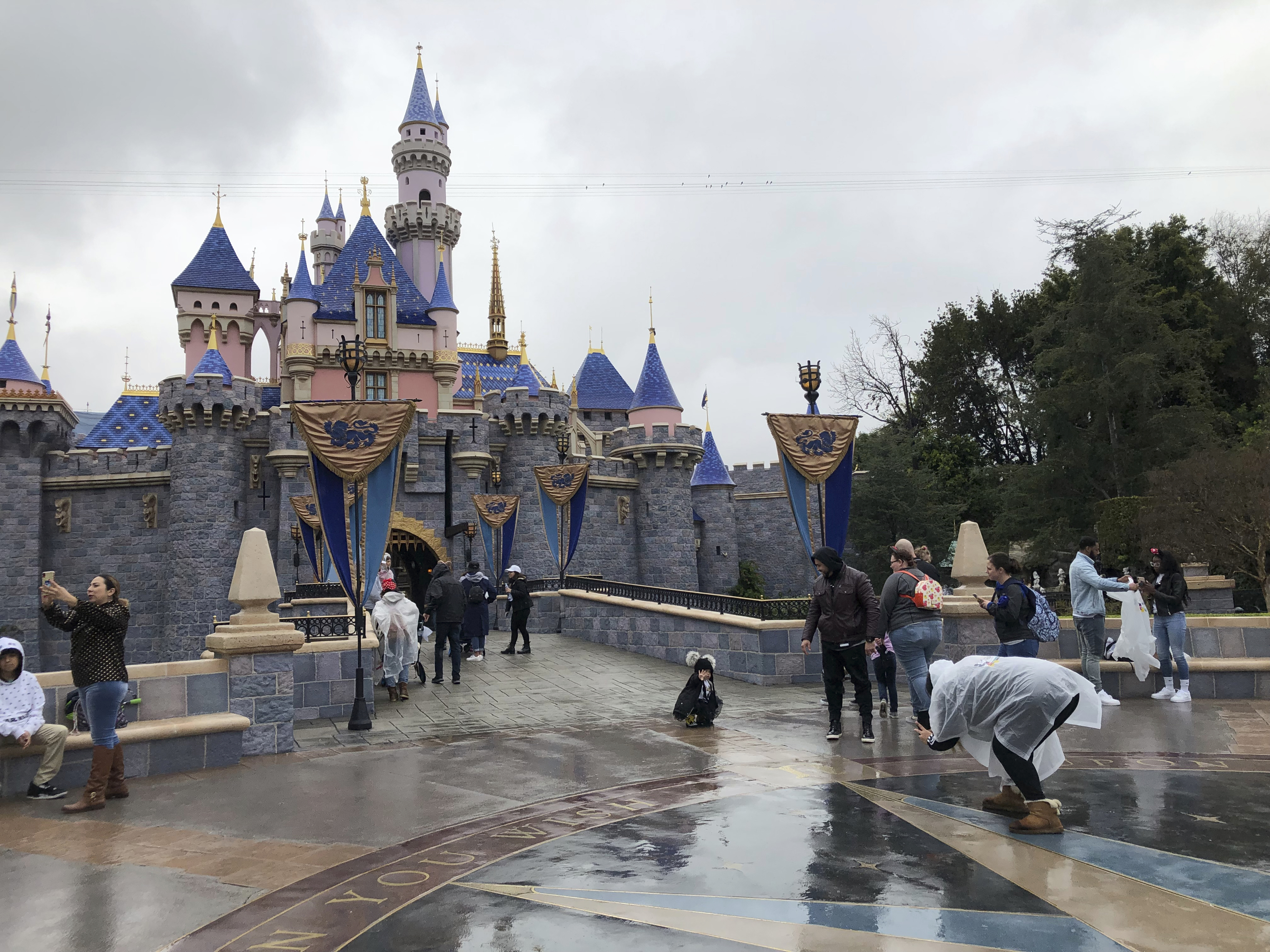 In this March 13, 2020, file photo, visitors take photos at Disneyland in Anaheim, Calif. Disney is proposing to reopen its Southern California theme parks in mid-July after a four-month closure due to the coronavirus, the company said on Wednesday, June 10, 2020. Disney is postponing the mid-July reopening of its Southern California theme parks until it receives guidelines from the state. The company announced Wednesday, June 23, 2020, an indefinite postponement for Disneyland and Disney California Adventure in Anaheim. Amy Taxin—AP Photo