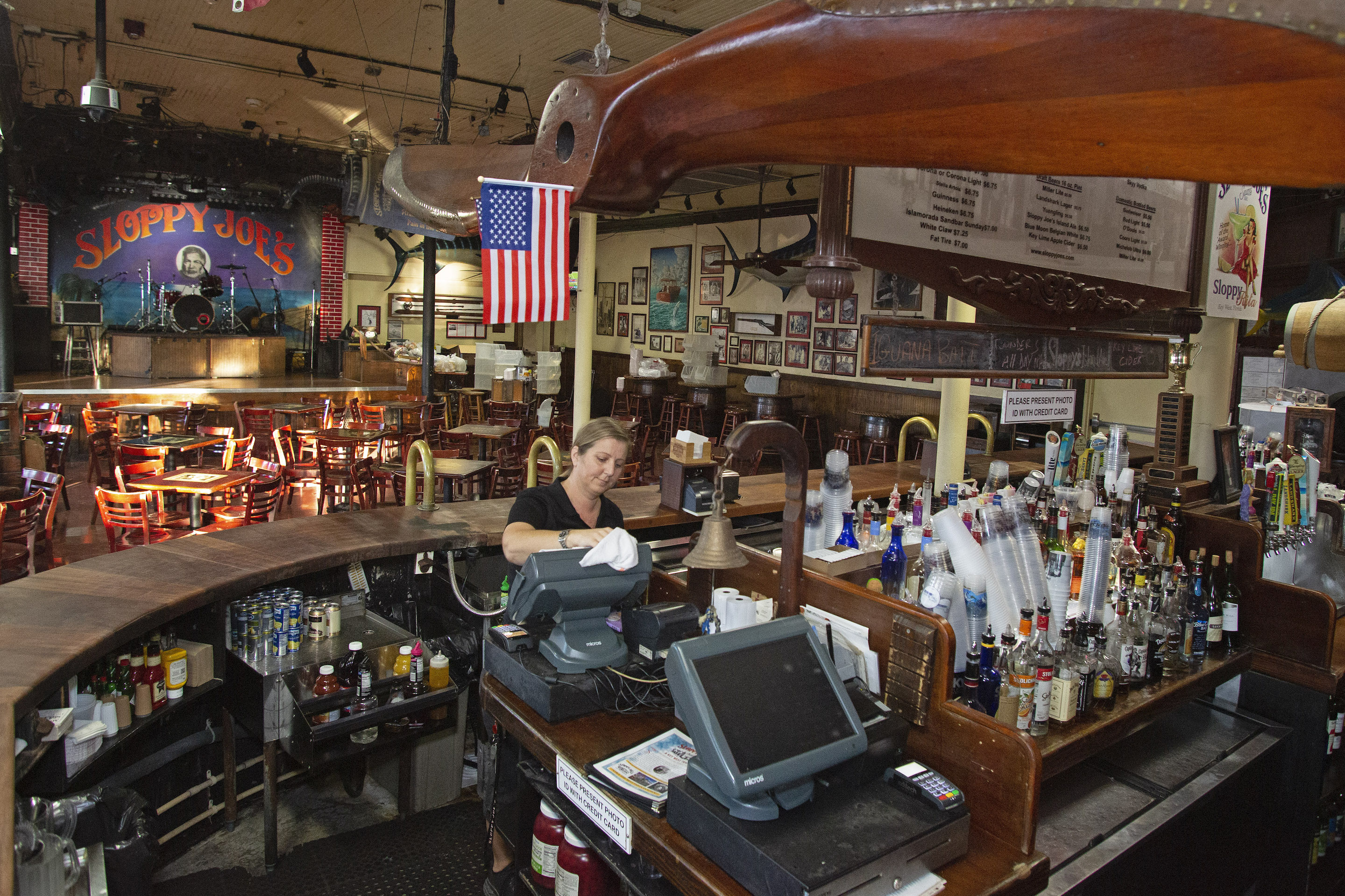 This handout photo provided by the Florida Keys News Bureau shows Becky Lawrence sanitizing a point of sale system at Sloppy Joes Bar on March 17, 2020, in Key West, Florida. - The iconic watering hole, a frequent hangout of the late writer Ernest Hemingway, was void of customers Tuesday evening as it joined other bars around Florida that closed under a state declaration signed by Gov. Ron DeSantis to help curb the spread of coronavirus. (Photo by Carol Tedesco / Florida Keys News Bureau / AFP) / XGTY / RESTRICTED TO EDITORIAL USE - MANDATORY CREDIT "AFP PHOTO / CAROL TEDESCO / FLORIDA KEYS NEWS BUREAU" - NO MARKETING NO ADVERTISING CAMPAIGNS - DISTRIBUTED AS A SERVICE TO CLIENTS --- (Photo by CAROL TEDESCO/Florida Keys News Bureau/AFP via Getty Images)
