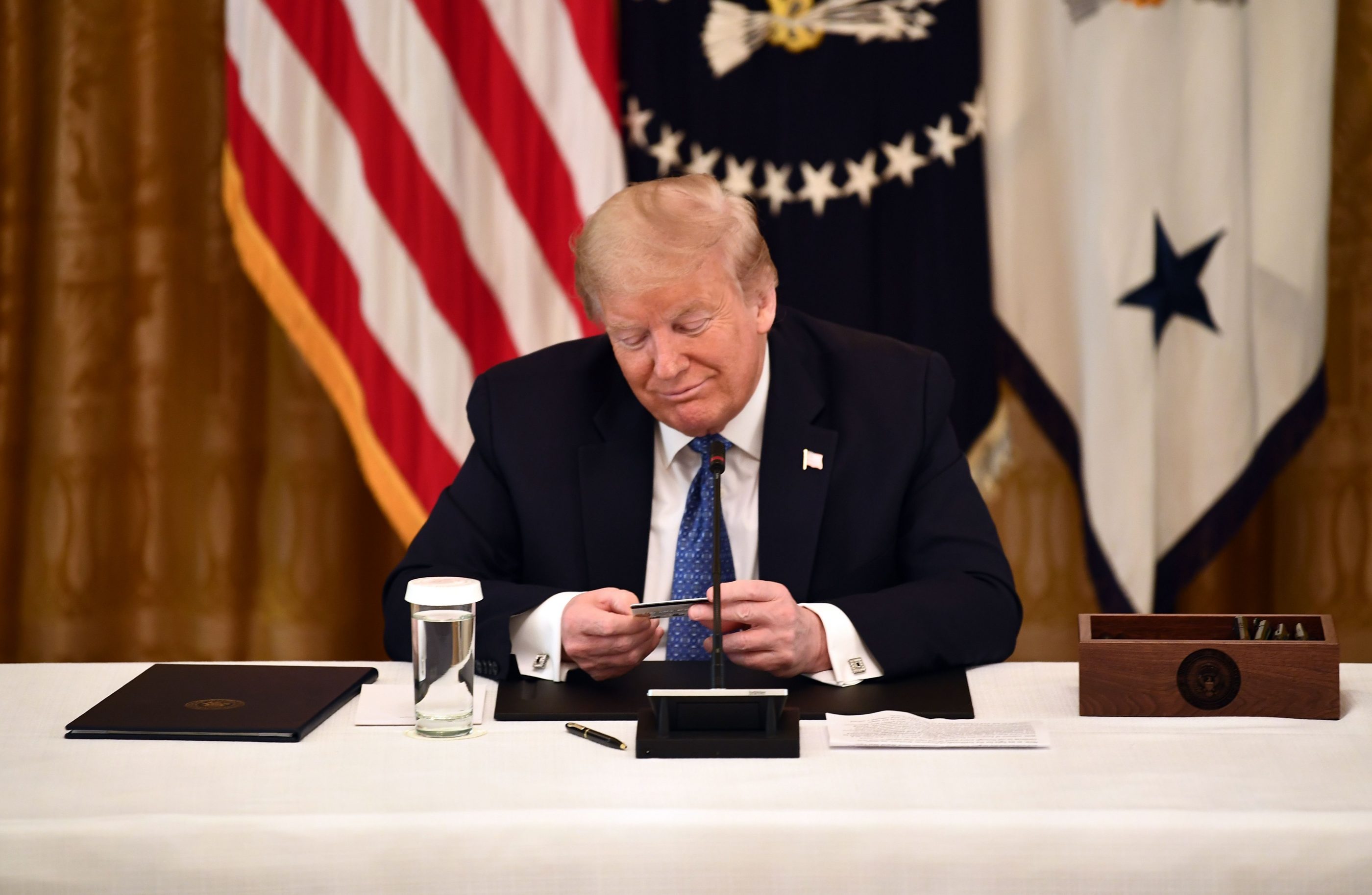 President Donald Trump—shown here examining a prepaid debit card used to deliver stimulus payments—reportedly supports additional direct payments to Americans. BRENDAN SMIALOWSKI—AFP/Getty Images