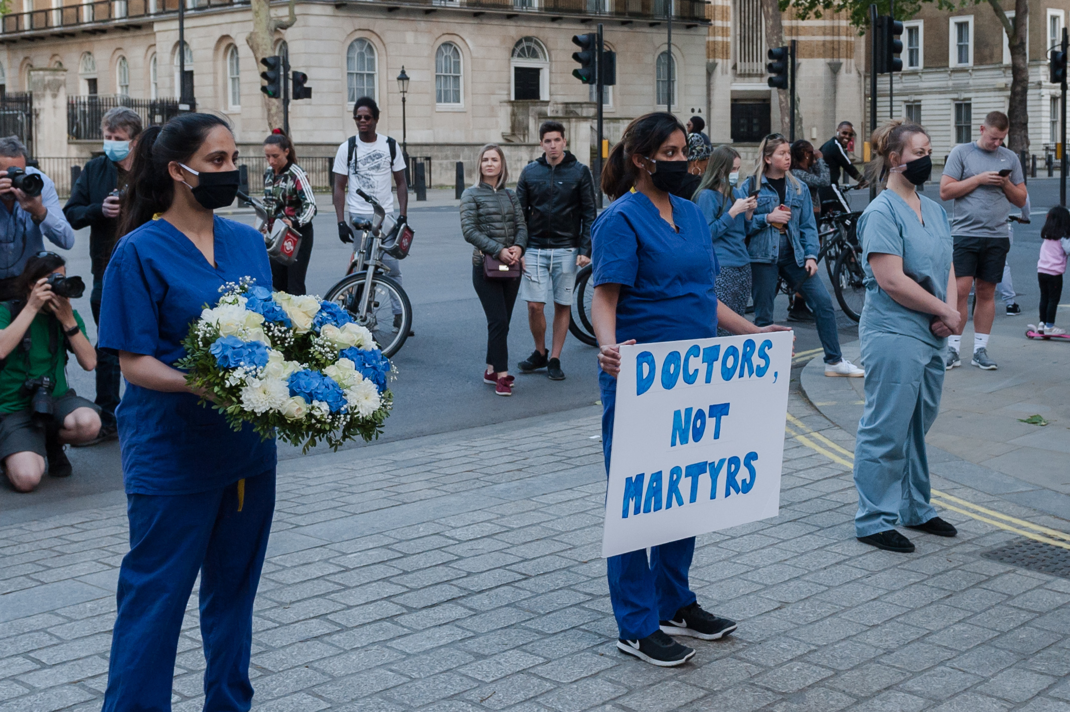 LONDON, UNITED KINGDOM - MAY 28, 2020: NHS staff hold a wreath and a placard saying 'Doctors Not Martyrs' as a part of a silent protest outside the gates of Downing Street during the weekly 'Clap for our Carers' applause for the NHS and key workers on the front line of the coronavirus (Covid-19) pandemic on 28 May, 2020 in London, England.- PHOTOGRAPH BY Wiktor Szymanowicz / Barcroft Studios / Future Publishing (Photo credit should read Wiktor Szymanowicz/Barcroft Media via Getty Images)