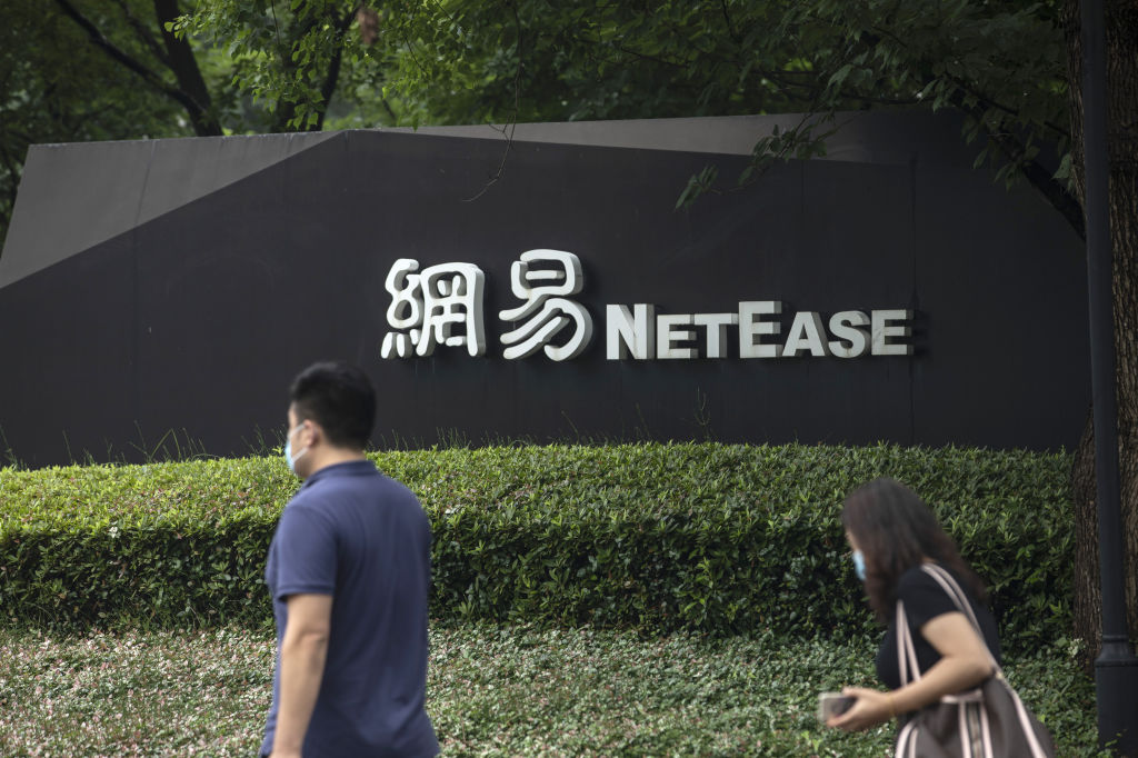 Pedestrians wearing protective masks walk past signage at the NetEase Inc. campus in Hangzhou, China, on Wednesday, June 10, 2020. NetEase Inc. soared more than 9% at the start of its first day of trading in Hong Kong on June 11, a solid debut that bodes well for a growing line-up of Chinese tech giants seeking to list closer to home. Qilai Shen—Bloomberg/Getty Images