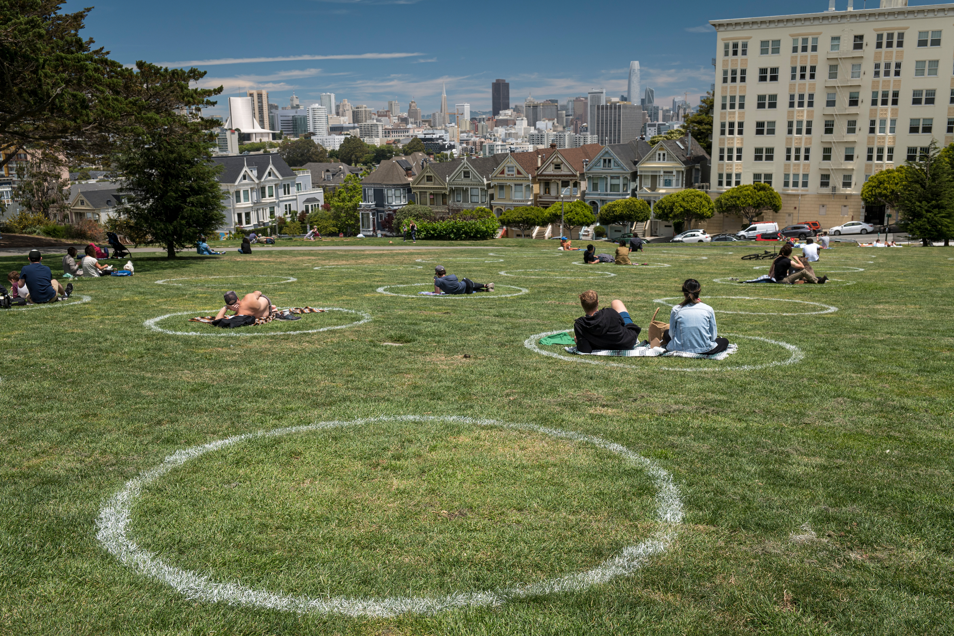 People lay on the grass in circles drawn to promote social distancing at Alamo Square in San Francisco, California, U.S., on Thursday, June 11, 2020. A second wave of coronavirus cases is emerging in the U.S., raising alarms as new infections push the overall count past 2 million Americans. Photographer: David Paul Morris/Bloomberg via Getty Images