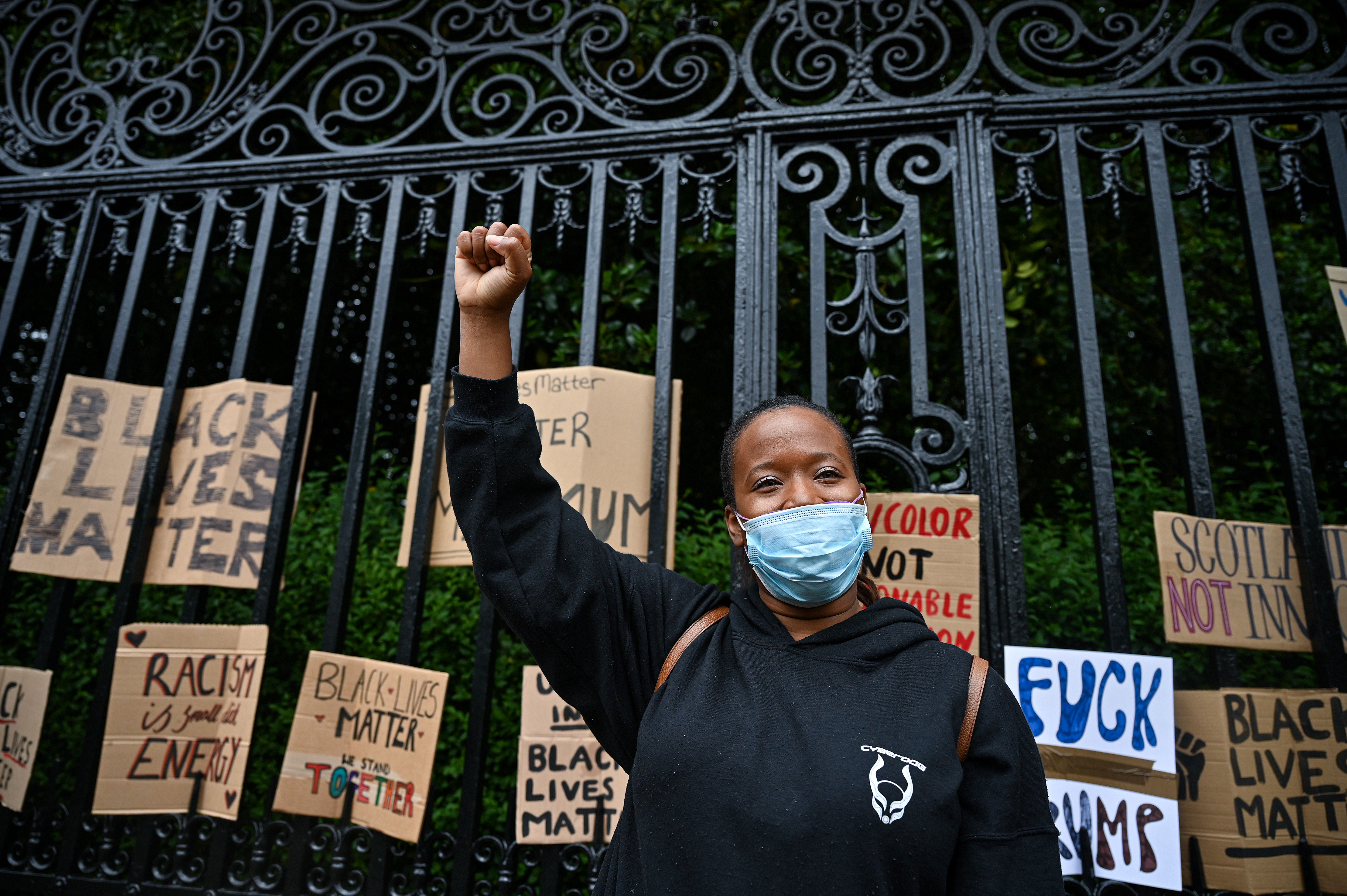 A woman raises her fist in the air as Black Lives Matter protesters hang their banners. Photo by Jeff J Mitchell/Getty Images)