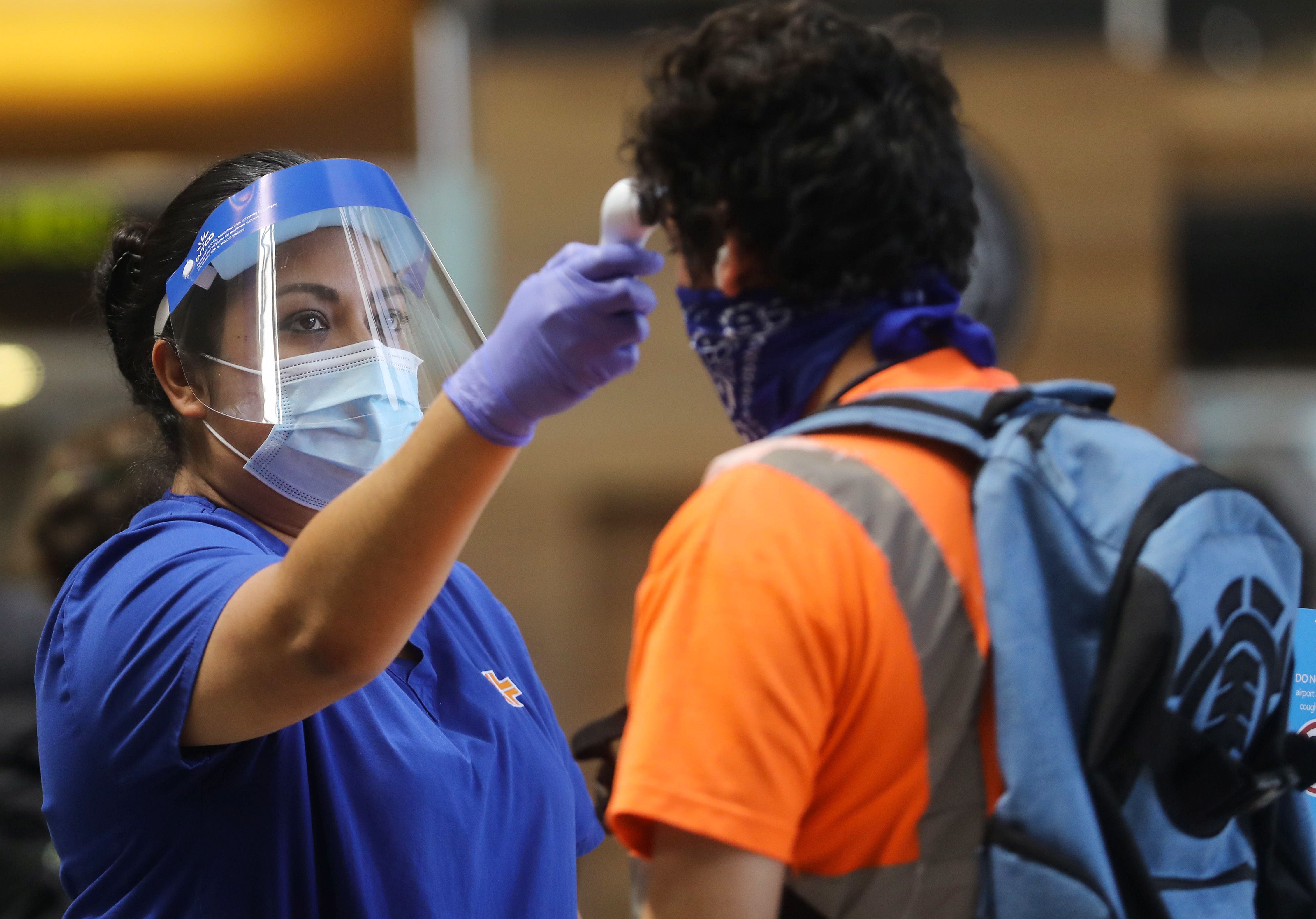 A traveler is checked with a handheld thermometer at Los Angeles International Airport. Cases are spiking around several American states, triggering Wednesday's steep sell-off in stocks. Wire photography: Mario Tama/Getty Images