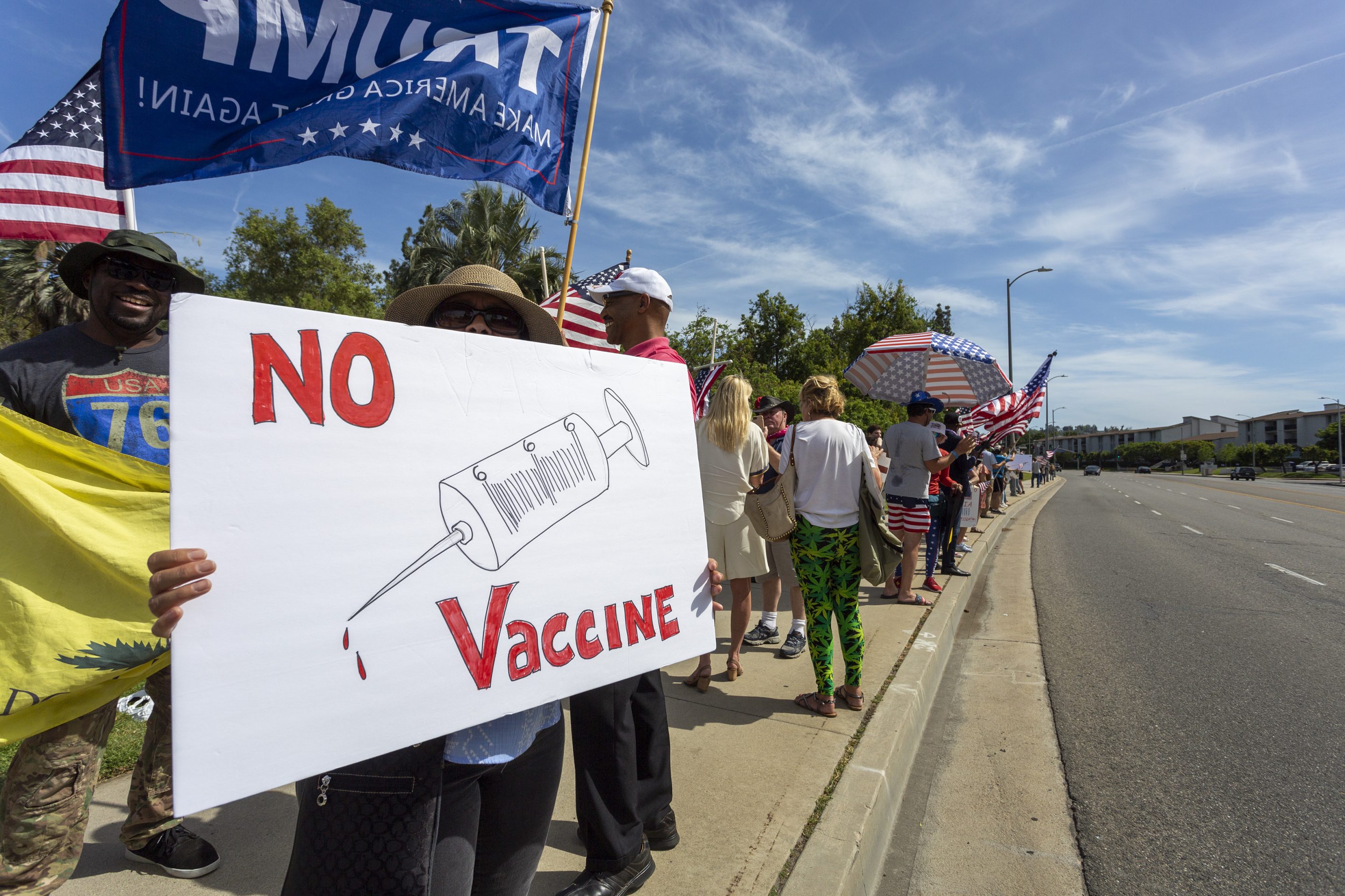 A protester holds an anti-vaccination sign as supporters of President Donald Trump rally to reopen California as the coronavirus pandemic continues to worsen, on May 16, 2020 in Woodland Hills, California.