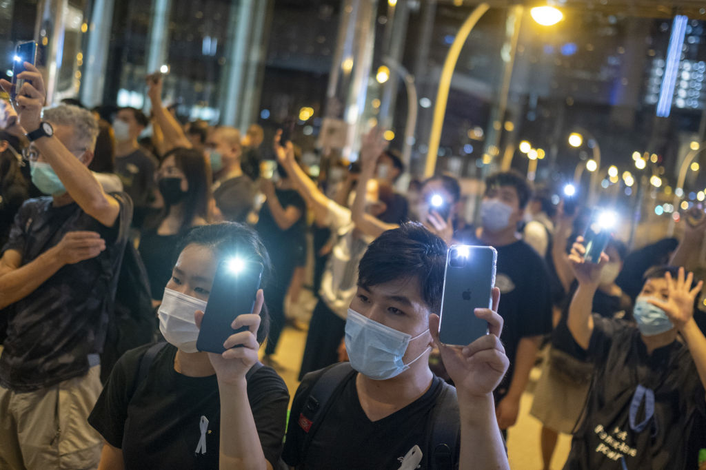 Demonstrators wearing protective masks shine lights from their smartphones at a memorial for a man who fell to his death during a protest one year ago at the Pacific Place shopping mall in Hong Kong, China, on Monday, June 15, 2020.Photographer: Justin Chin/Bloomberg via Getty Images