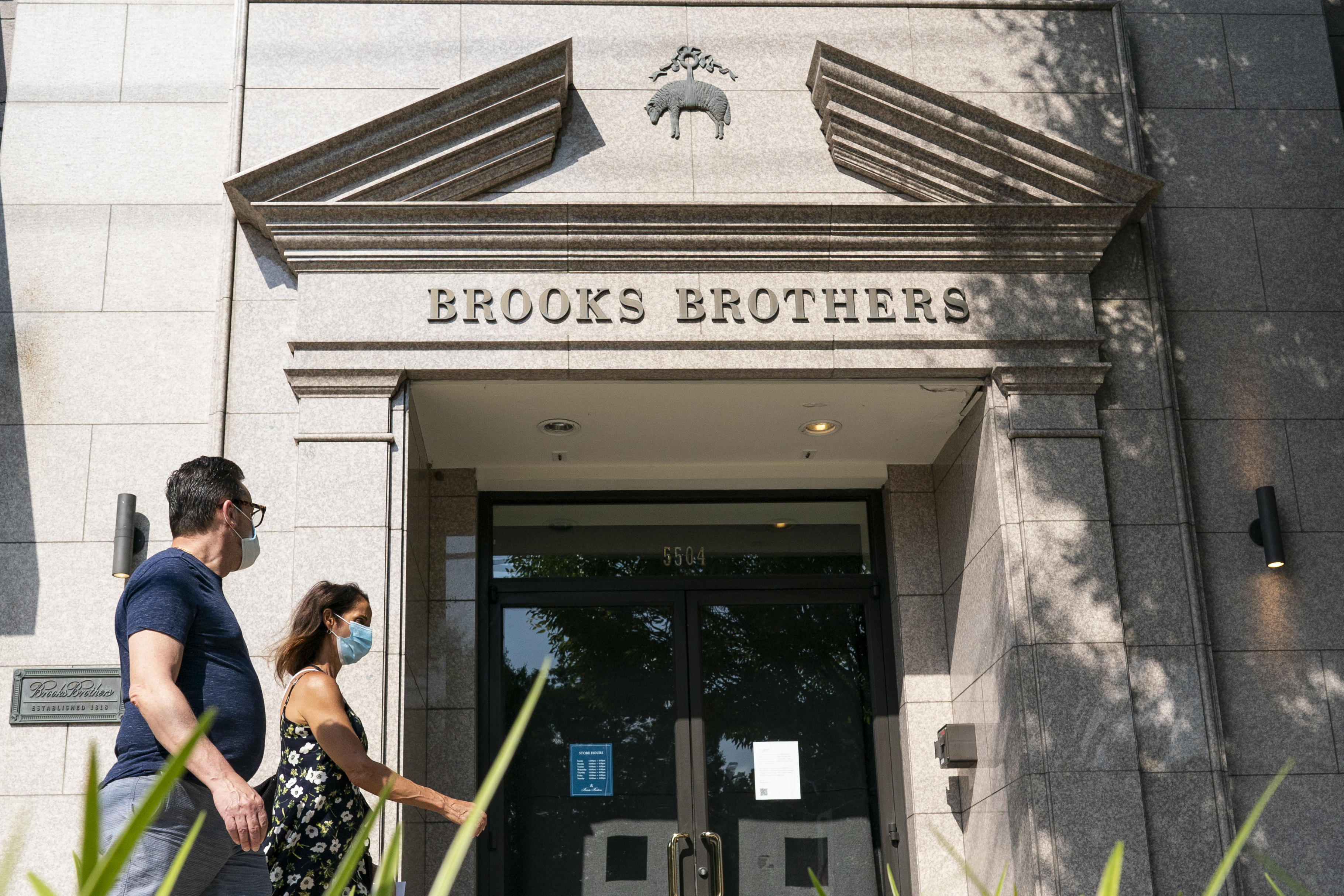 Pedestrians in Chevy Chase, Maryland, U.S., wearing protective masks walk past a Brooks Brothers store on Wednesday, July 8, 2020. Brooks Brothers Group Inc. filed for bankruptcy, felled by the coronavirus pandemic's impact on clothing sales and its own heavy debt load. Photographer: Alex Edelman/Bloomberg via Getty Images