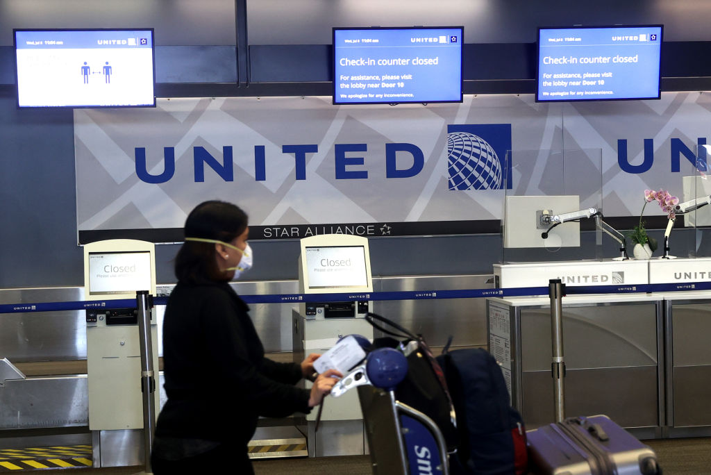 A United Airlines passenger pushes a luggage cart past closed check-in kiosks at San Francisco International Airport on July 8, 2020 in San Francisco, Calif. As the coronavirus COVID-19 pandemic continues, United Airlines has sent layoff warnings to 36,000 of its front line employees to give them a 60 day notice that furloughs or pay cuts could occur after October 1.