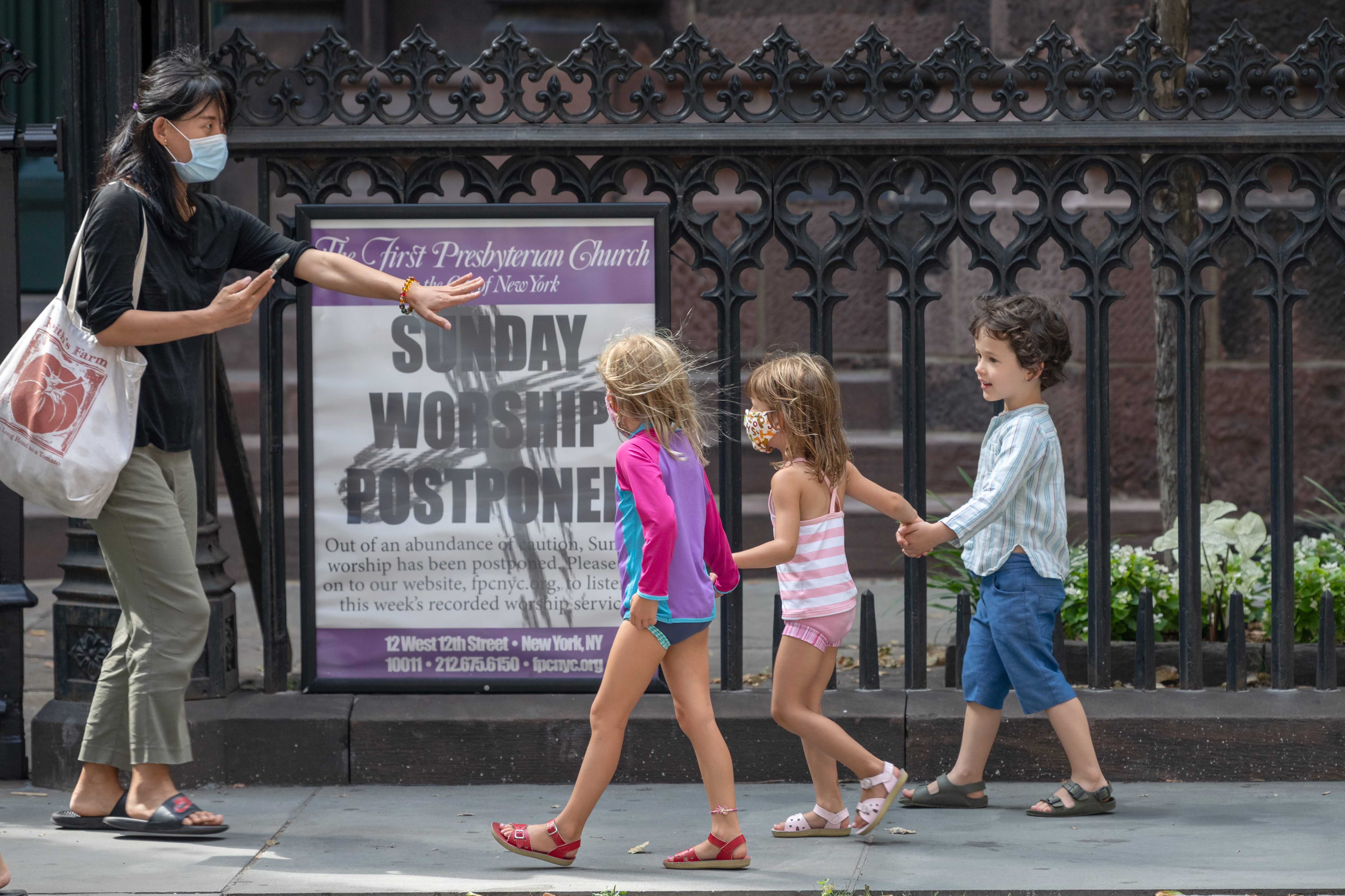 NEW YORK, NEW YORK - JULY 28: A caregiver wearing a mask stops children holding hands to take a photo of them as the city continues Phase 4 of re-opening following restrictions imposed to slow the spread of coronavirus on July 28, 2020 in New York City. The fourth phase allows outdoor arts and entertainment, sporting events without fans and media production. (Photo by Alexi Rosenfeld/Getty Images)
