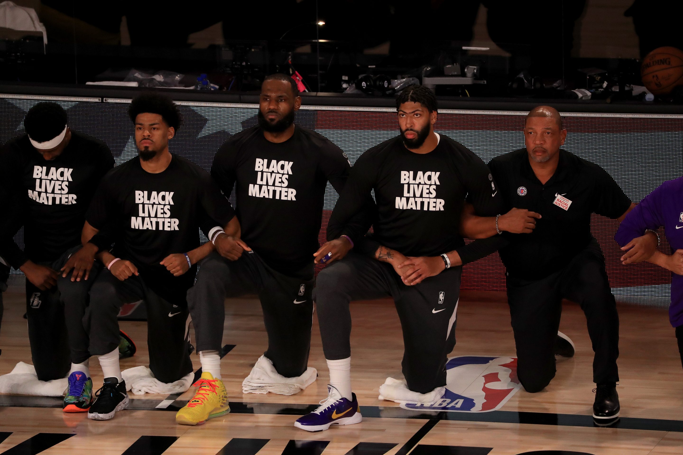 LeBron James and Anthony Davis of the Los Angeles Lakers in a Black Lives Matter Shirt kneel with their teammates during the national anthem prior to the game against the L.A. Clippers on July 30, 2020.