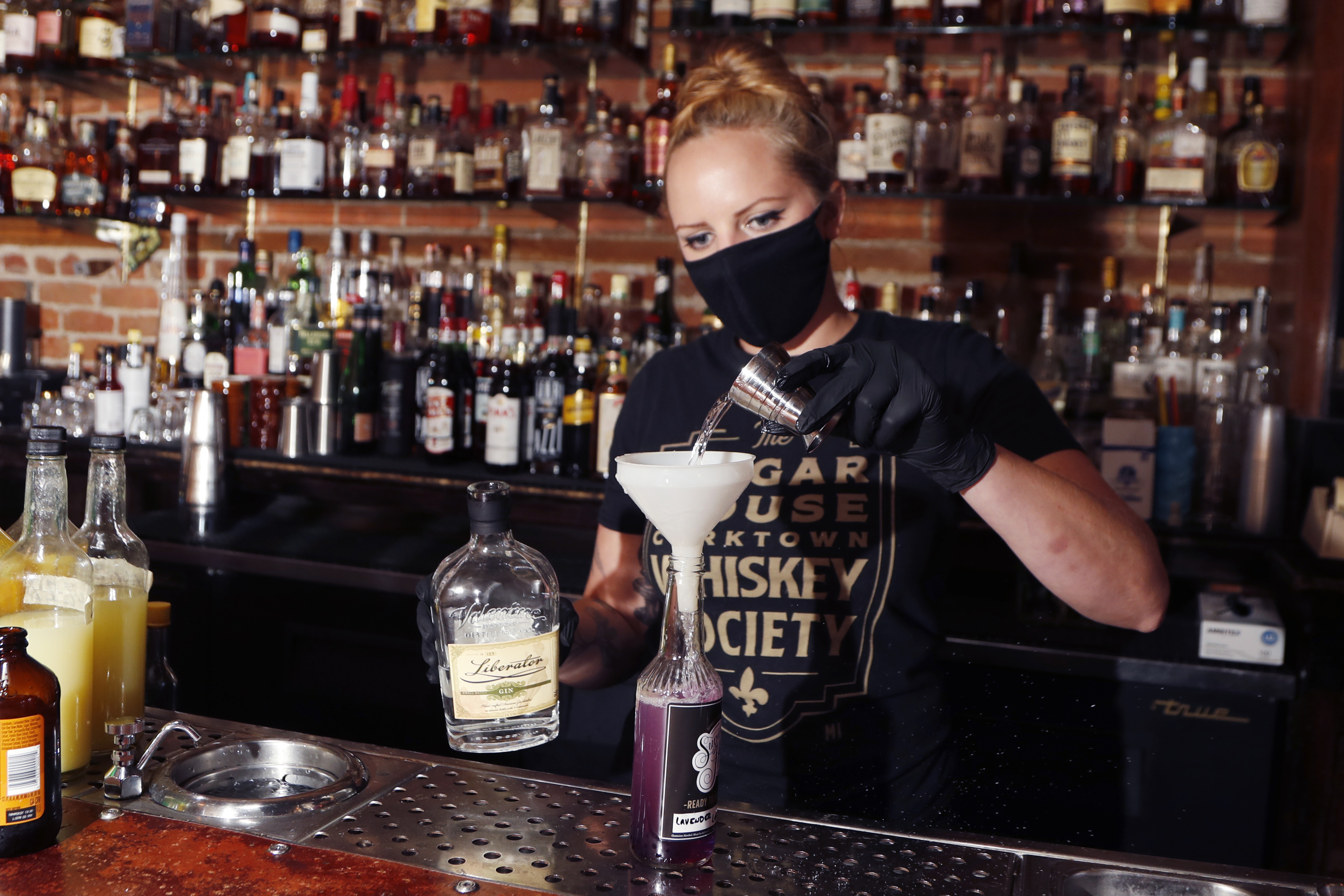 Sugar House bartender Shelby Minnix creates a Lavender Lemonade cocktail in a to-go bottle, Thursday, Aug. 13, 2020, in Detroit. At least 33 states and the District of Columbia are temporarily allowing cocktails to-go during the pandemic, up from around three before the coronavirus struck. AP Photo/Carlos Osorio