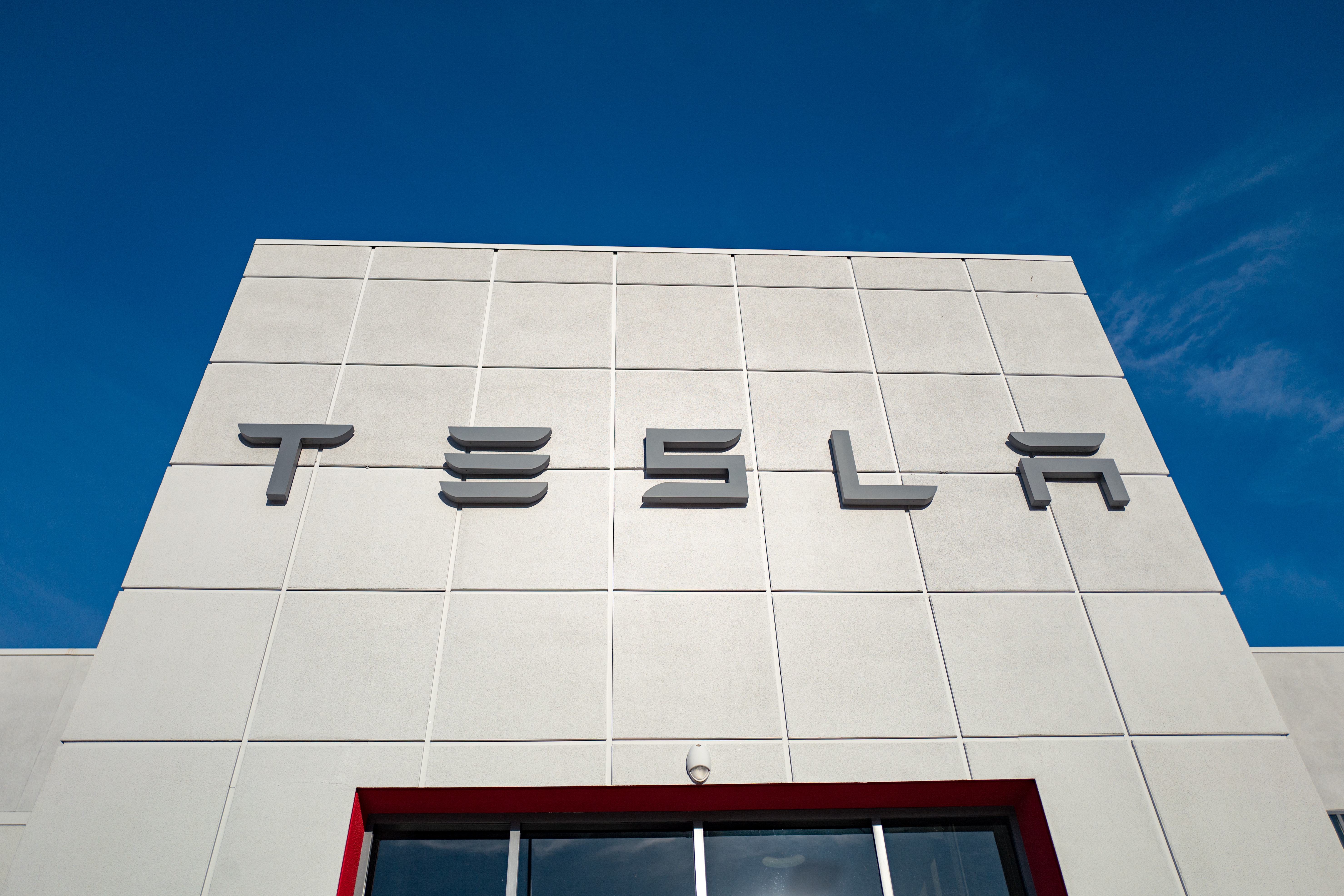 Low-angle view of the facade of Tesla Motors dealership with logo and sign in Pleasanton, California, July 23, 2018.