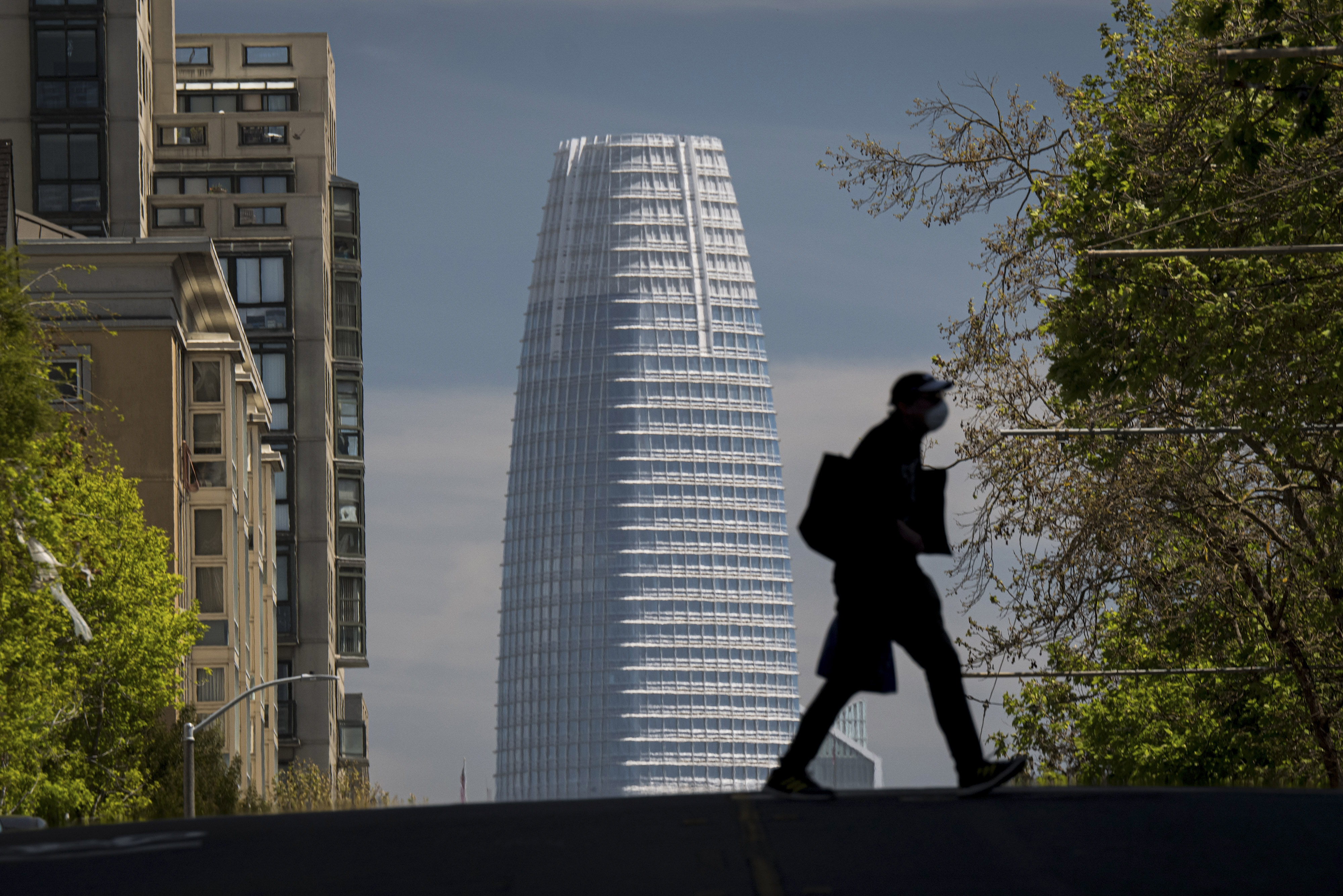 A person wearing a protective mask crosses Post Street in front of SalesForce Tower in San Francisco, California, U.S., on Wednesday, April 15, 2020. California Governor Gavin Newsom on Tuesday laid out rough benchmarks for reopening his state's economy - and radically reshaping daily life in the process - as he tried to bring other states into his West Coast coalition to fight the new coronavirus. Photographer: David Paul Morris/Bloomberg via Getty Images