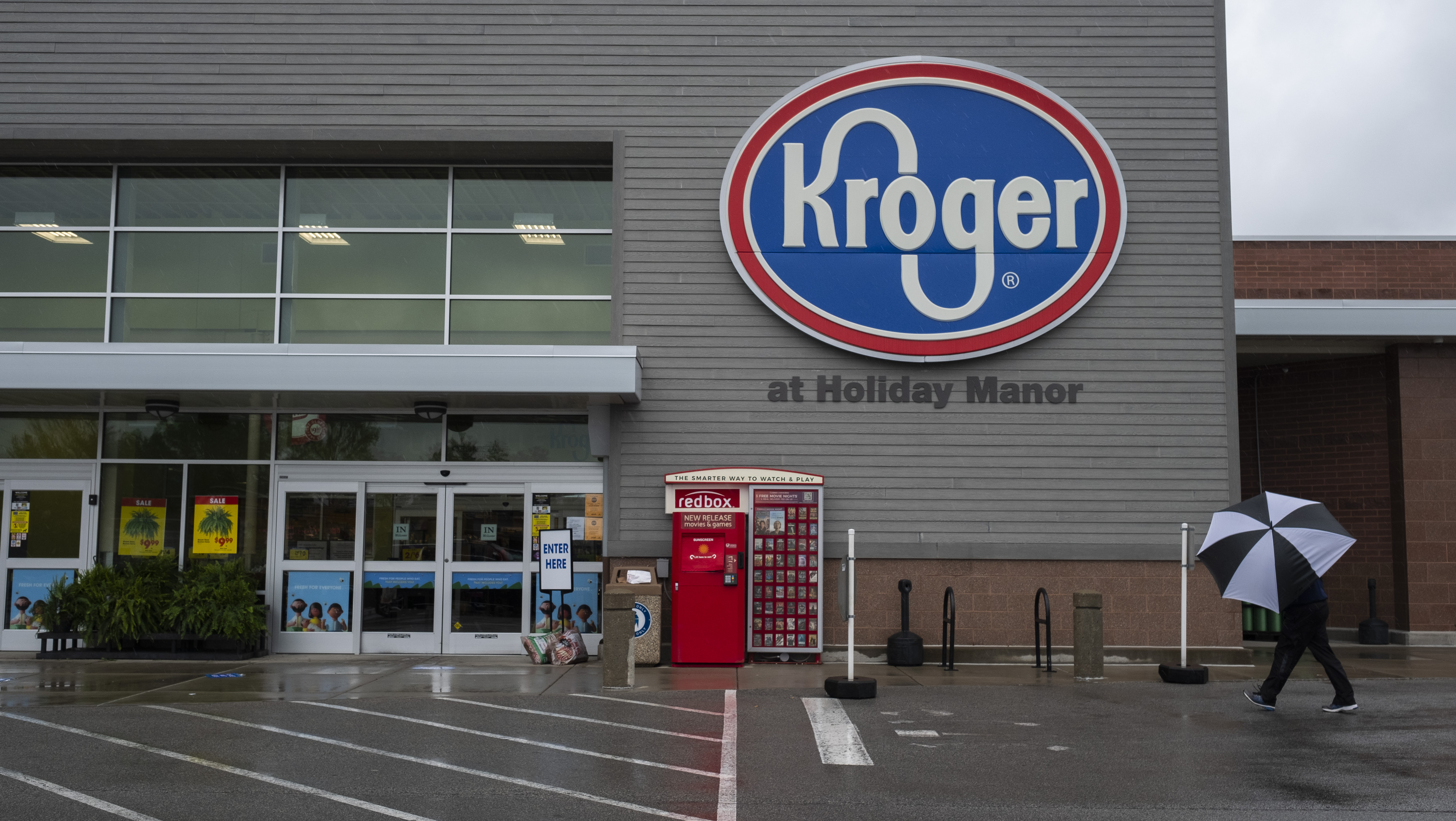 A shopper holding an umbrella walks towards a Kroger Co. grocery store in Louisville, Kentucky, U.S., on Sunday, April 26, 2020.