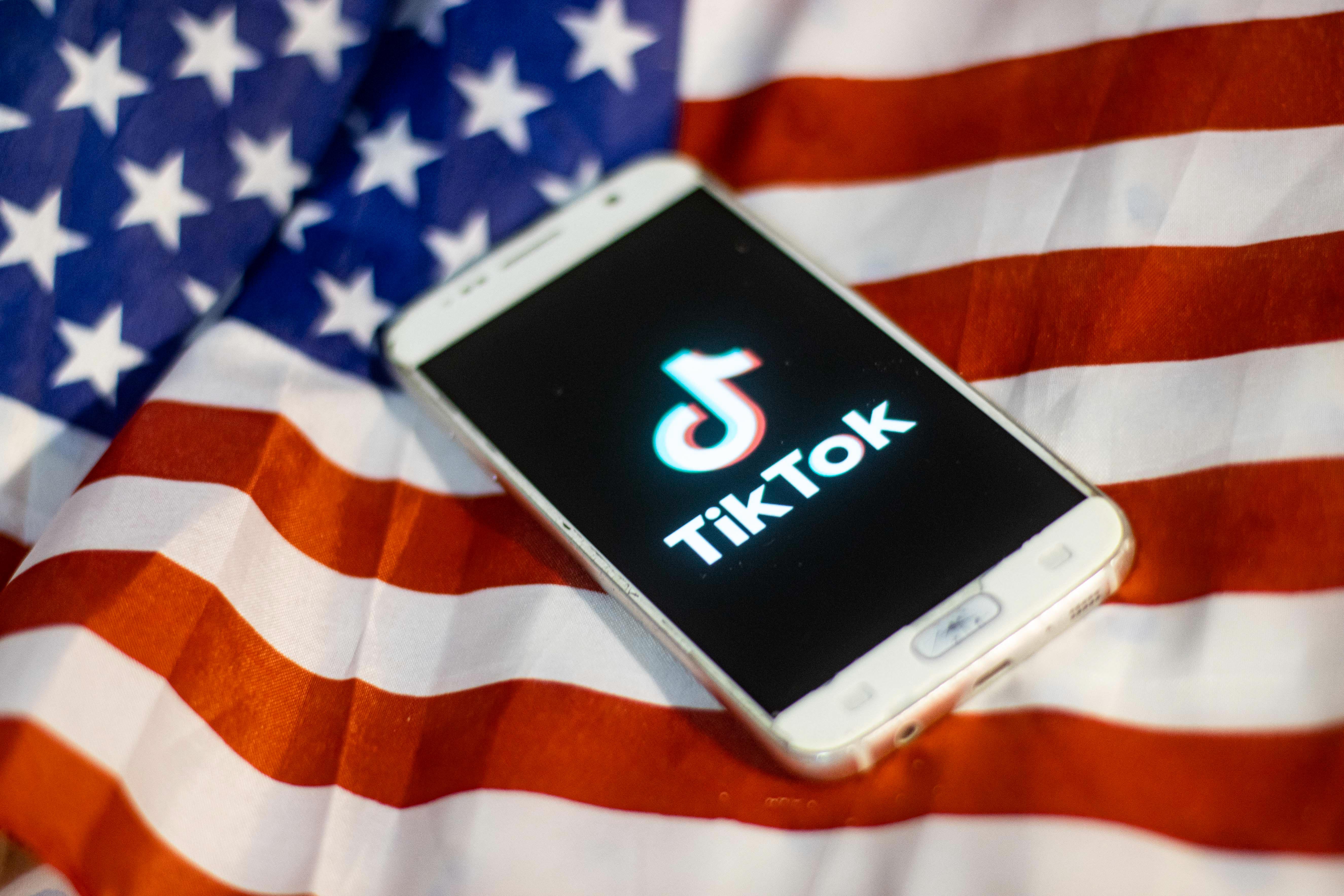 TikTok closeup logo displayed on a phone screen, smartphone on the American flag or U.S. flag, the national flag of the United States are seen in this multiple exposure illustration. Tik Tok is a Chinese video-sharing social networking service owned by a Beijing based internet technology company, ByteDance. It is used to create short dance, lip-sync, comedy and talent videos. ByteDance launched TikTok app for iOS and Android in 2017 and earlier in September 2016 Douyin fror the market in China. TikTok became the most downloaded app in the US in October 2018. President of the USA Donald Trump is threatening and planning to ban the popular video sharing app TikTok from the US because of the security risk. On August 3, 2020 in Thessaloniki, Greece.