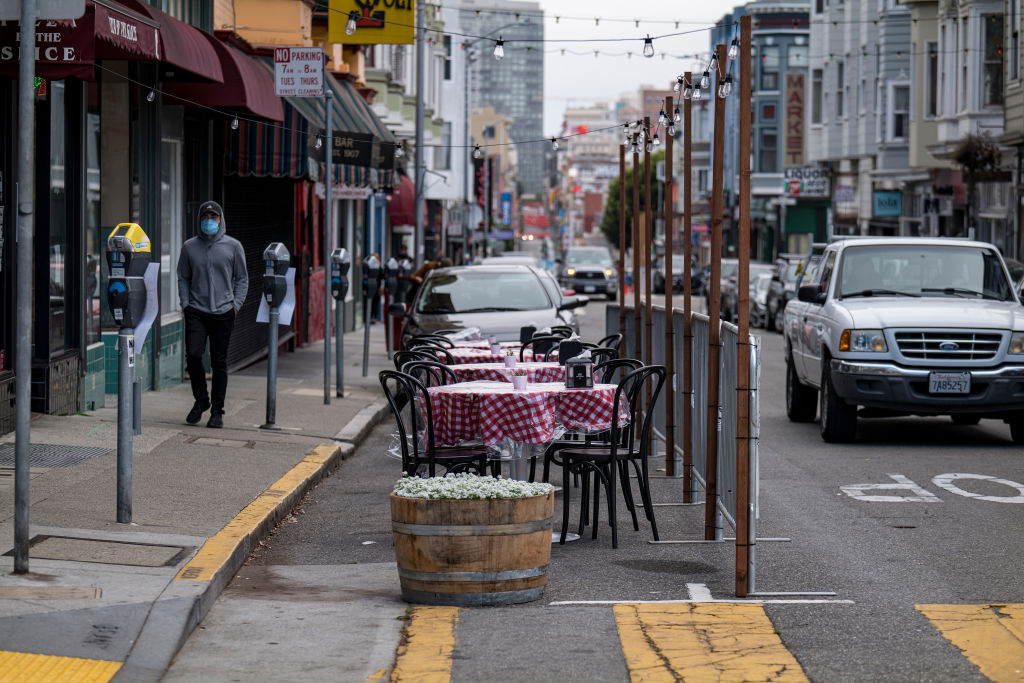 A person wearing a protective mask walks past an outdoor dining area at a restaurant in San Francisco, California, U.S., on Wednesday, Aug. 5, 2020. California's second round of coronavirus-related shutdowns, among the nation's strictest measures, are already causing pain for the most populous state's labor market and portend a deterioration in the overall U.S. employment picture for July.
