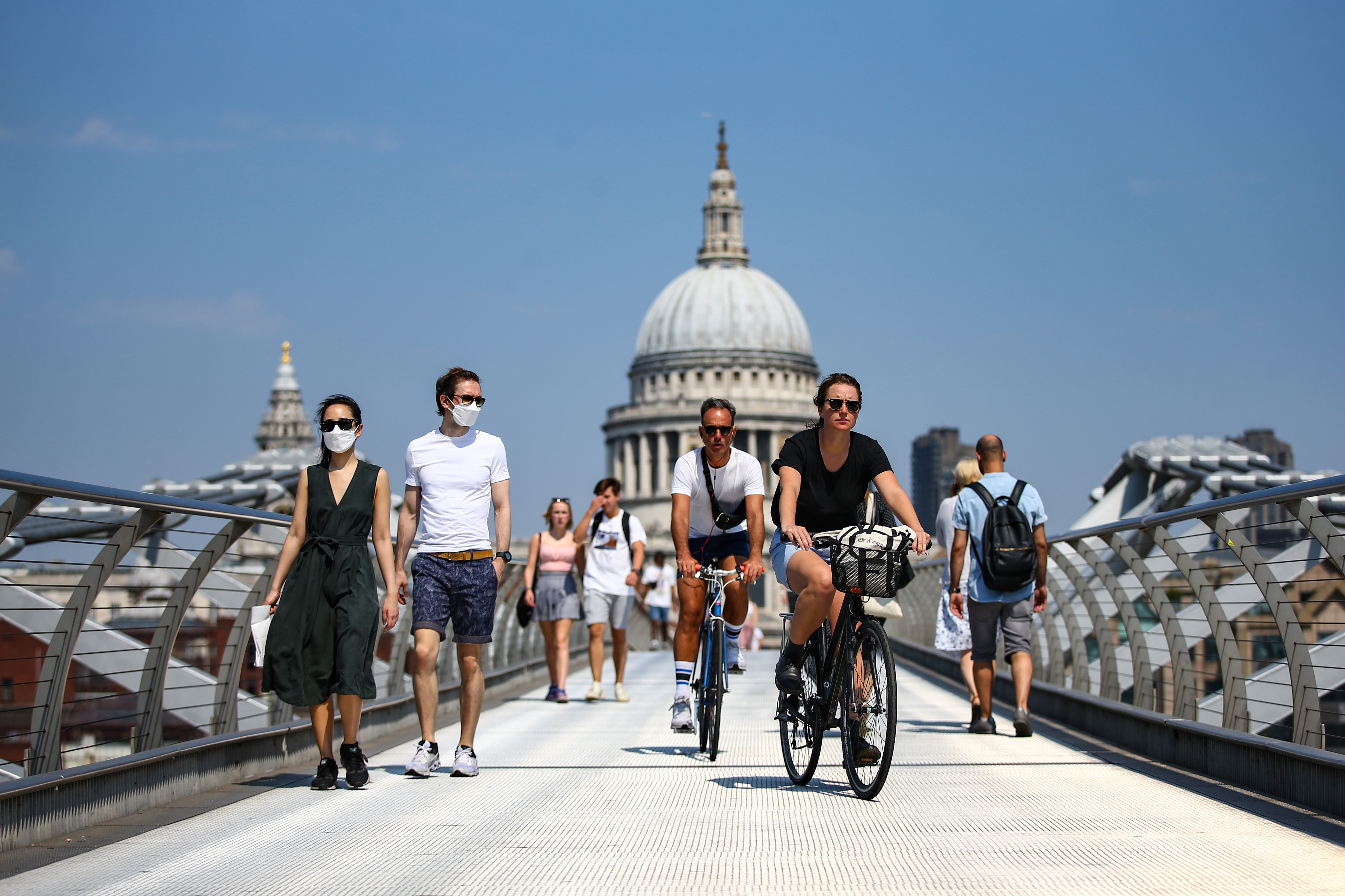 LONDON, ENGLAND - AUGUST 09: People wearing faces mask cross the Millennium Bridge on August 9, 2020 in London, United Kingdom. Southern England saw several days of high temperatures, with the mercury hitting 36.4C at Heathrow and Kew Gardens, England's hottest August day in 17 years. (Photo by Hollie Adams/Getty Images)