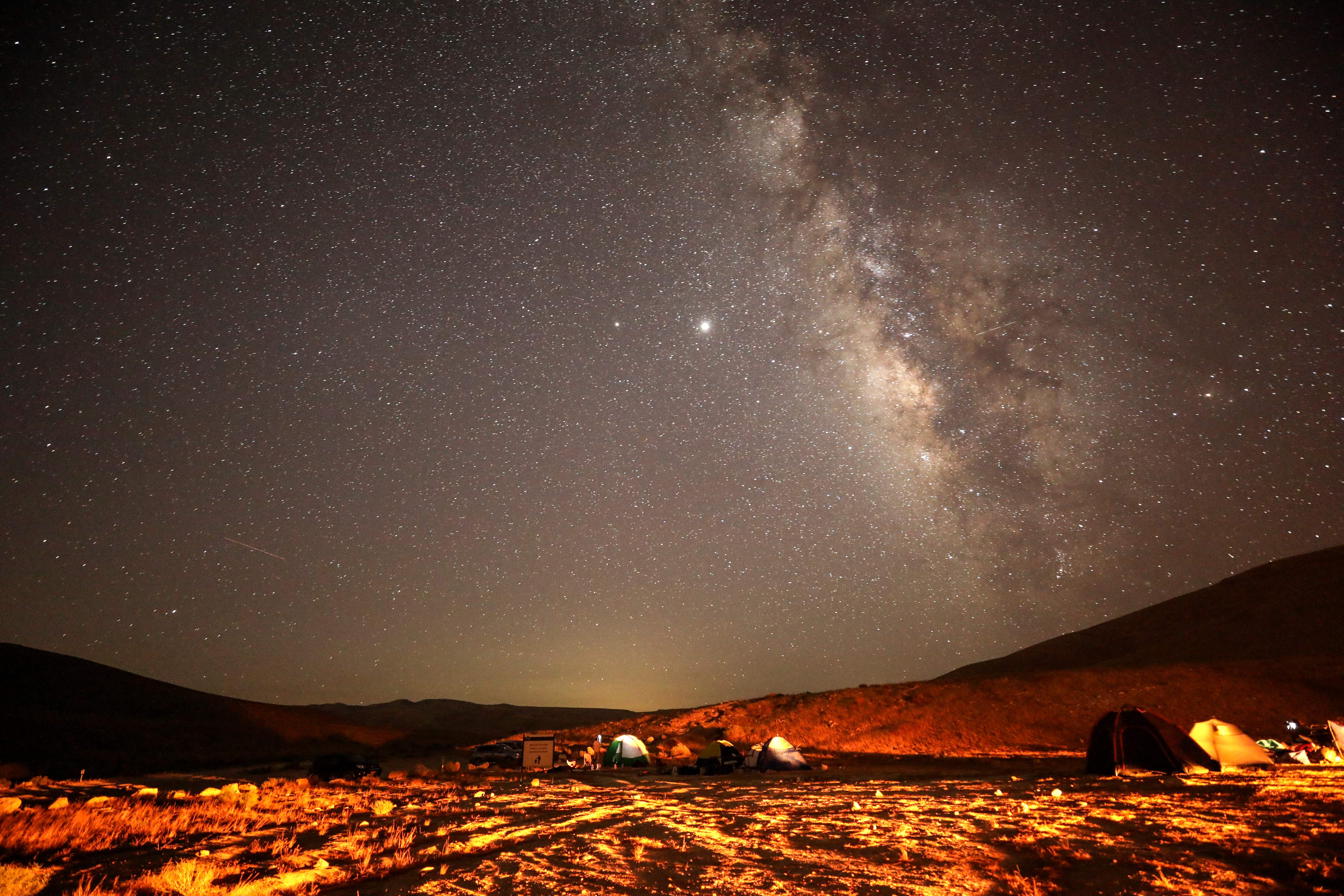 A Perseid meteor streaks across the sky above a camping site at the Negev desert near the city of Mitzpe Ramon on August 11, 2020 during the Perseids meteor shower, which occurs every year when the Earth passes through the cloud of debris left by the comet Swift-Tuttle. 