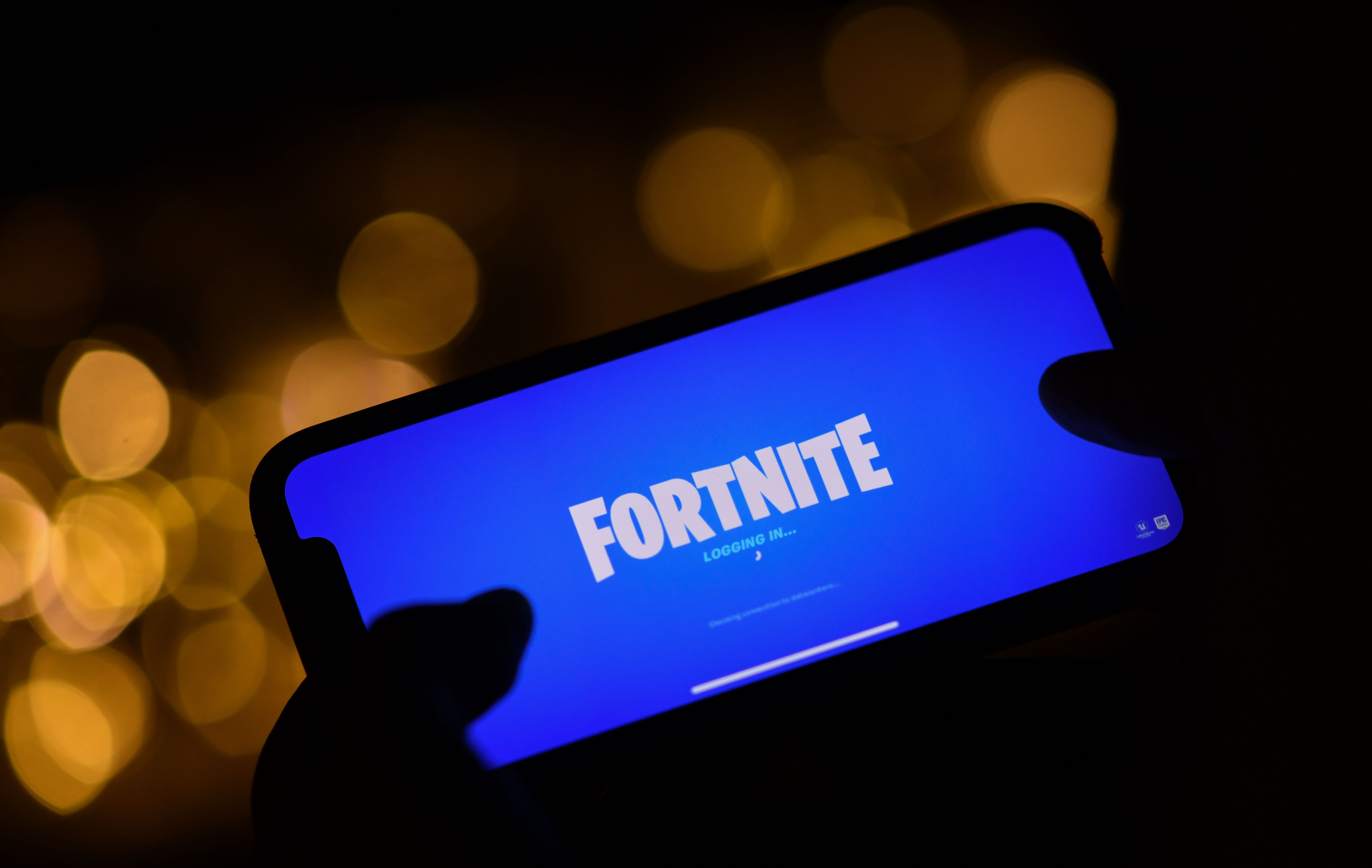 This illustration picture shows a person logging into Epic Games' Fortnite on their smartphone in Los Angeles on August 14, 2020. - Apple and Google on August 13, 2020 pulled video game sensation Fortnite from their mobile app shops after its maker Epic Games released an update that dodges revenue sharing with the tech giants.