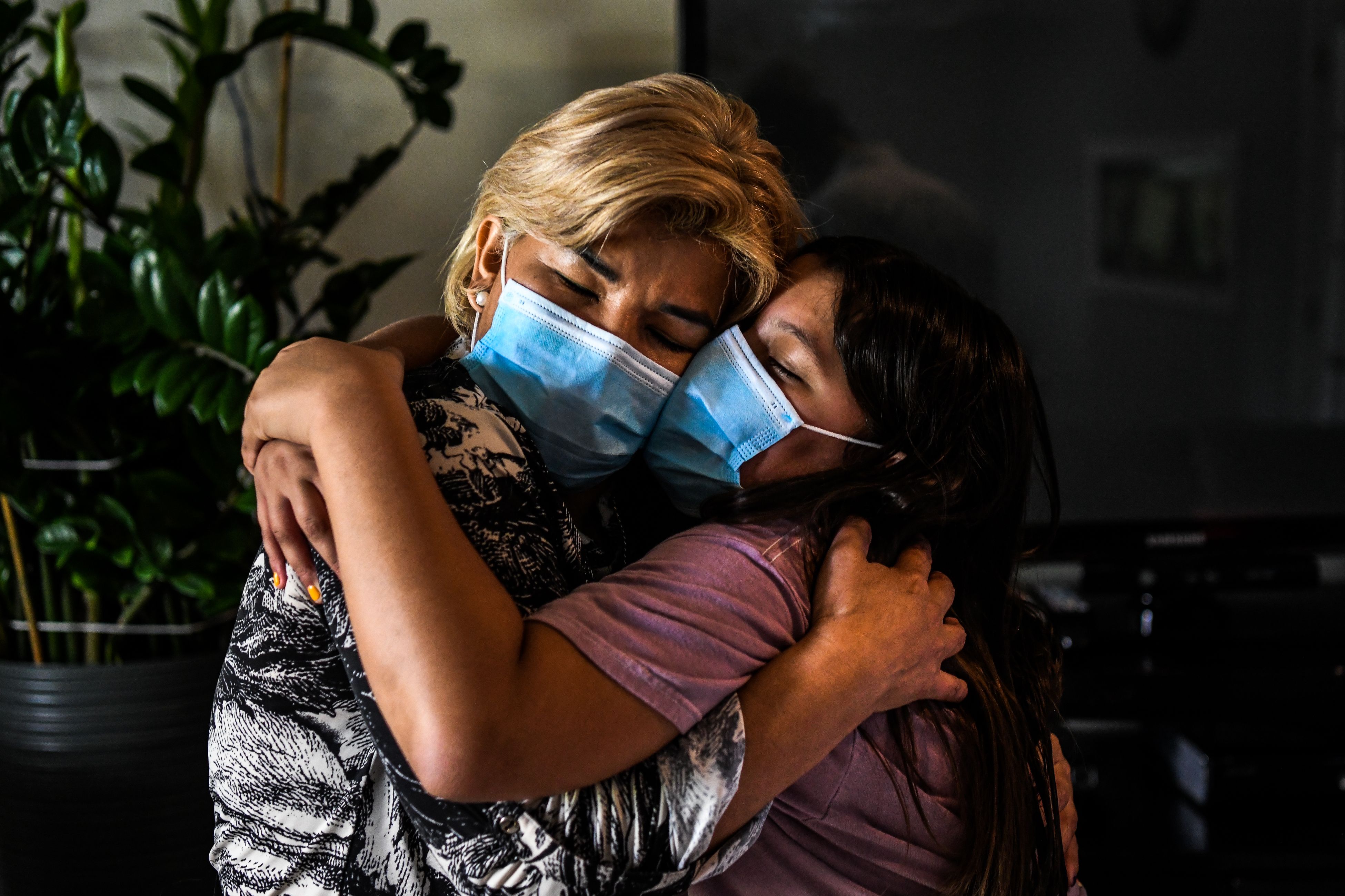 Coronavirus survivors Azareth Amaya Gamez (R) embraces her mother Glenda Yaneth Amaya Gamez (L) inside their home in Miami Gardens near Miami, on August 11, 2020. - Until the coronavirus crisis erupted, German Amaya worked at the luxury Fontainebleau hotel in Miami. But then he lost his job, and his health insurance -- and eventually, his life. Amaya died in a Florida hospital after a long battle with COVID-19, the disease caused by the novel coronavirus. (Photo by CHANDAN KHANNA / AFP) (Photo by CHANDAN KHANNA/AFP via Getty Images)