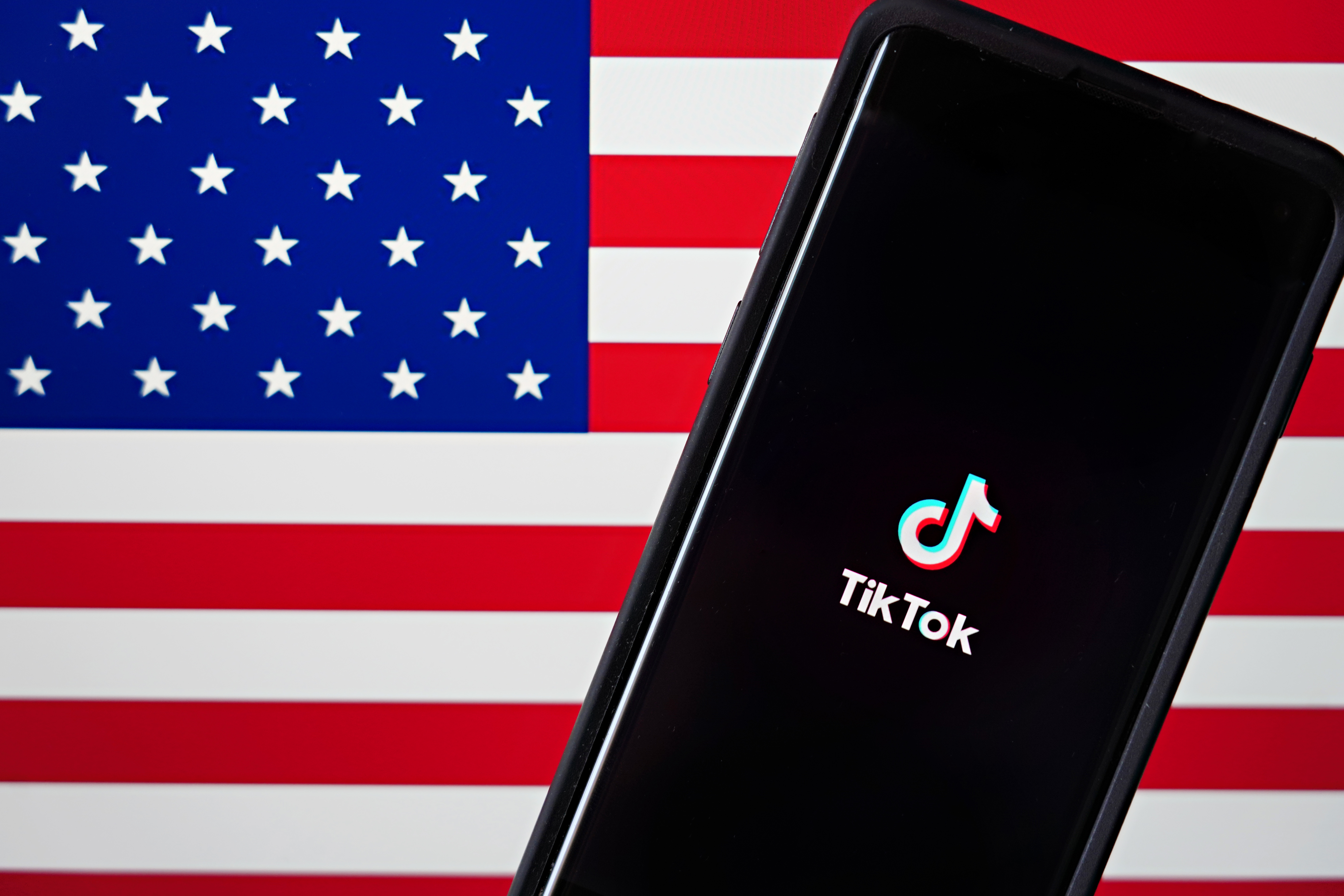 NEW YORK, NEW YORK - AUGUST 03: In this photo illustration, a mobile phone featuring the TikTok app is displayed next to the American flag on August 03, 2020 in New York City. Under threat of a U.S. ban on the popular social media app, it has been reported that Microsoft is considering taking over from Chinese firm ByteDance. (Photo Illustration by Cindy Ord/Getty Images)