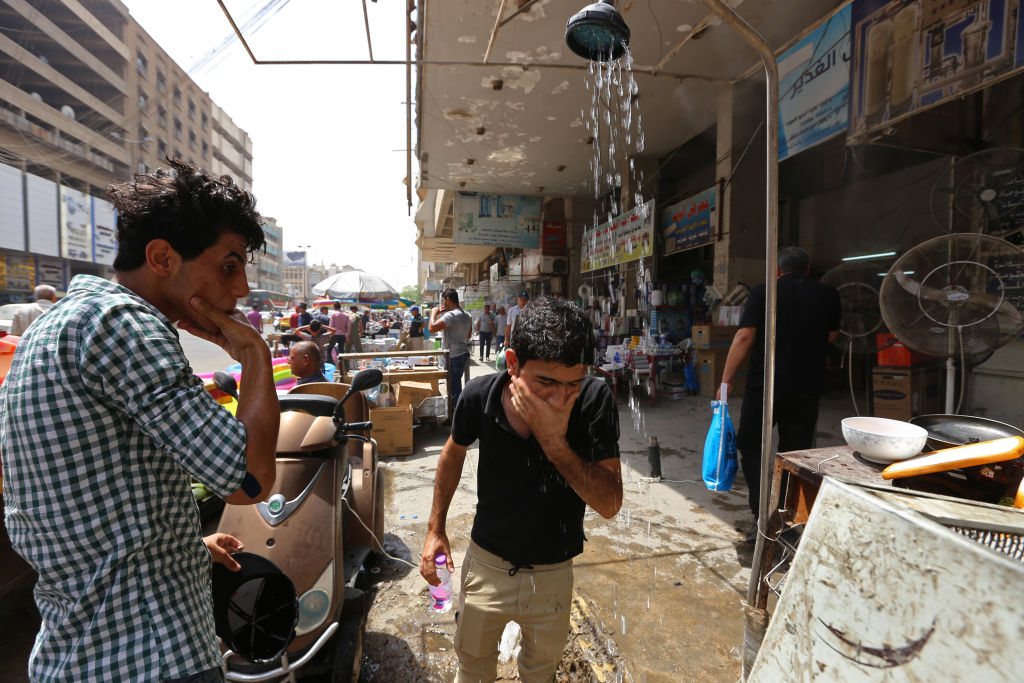 In Iraq, enterprising residents have taken too erecting makeshift showers on the street to provide respite from the heat. SABAH ARAR/AFP via Getty Images