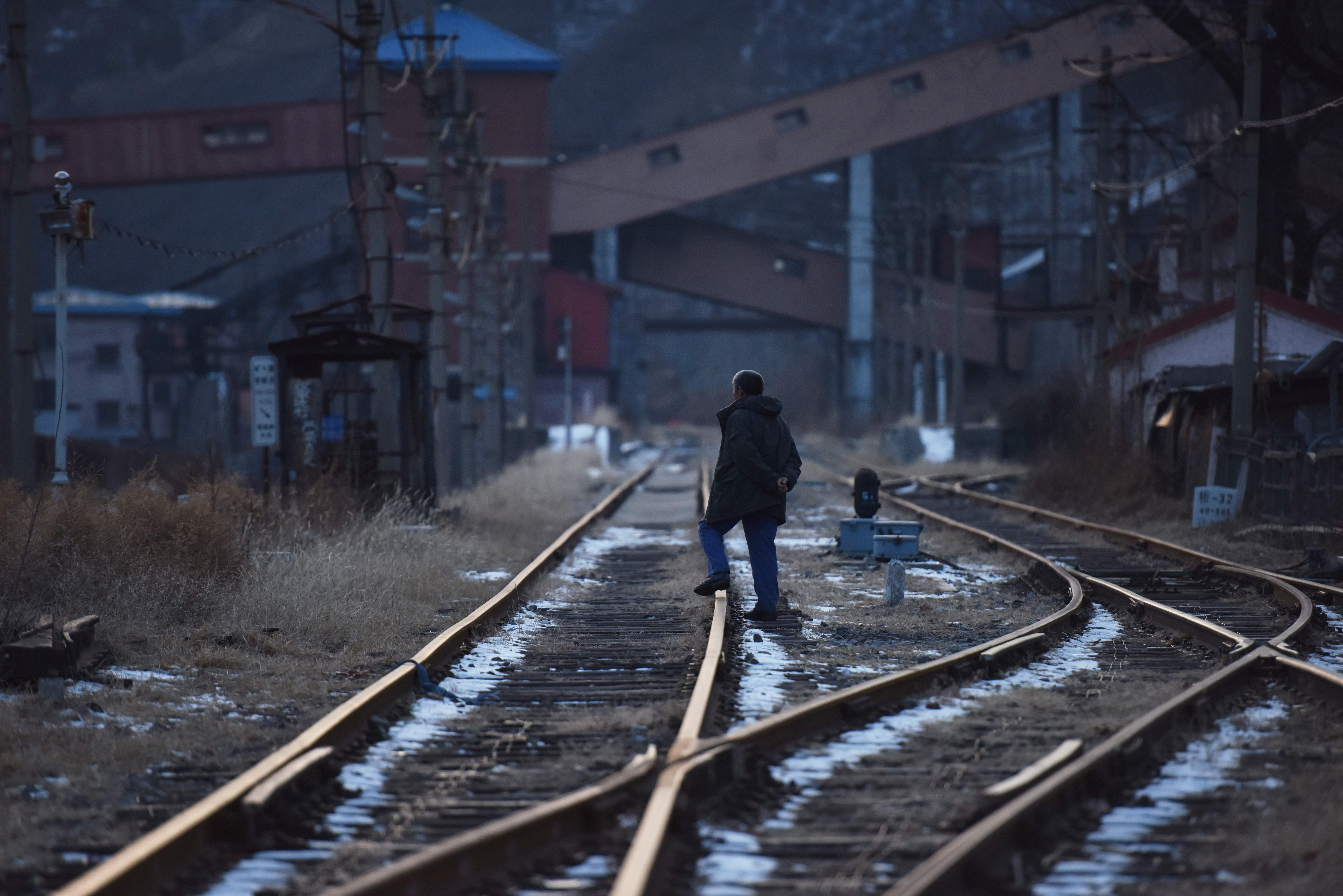 This photo taken on December 18, 2019 shows a man walking along a railway line outside the Datai coal mine in Mentougou, west of Beijing. - Mentougou, one of China's oldest mining towns, has powered the capital for nearly 300 years but more than 270 coal mines in the area have been shut down over the past two decades as China scambles to cut carbon emissions and switch to renewables. (Photo by GREG BAKER / AFP) / TO GO WITH China-environment-coal,FEATURE by Poornima WEERASEKARA and Danni ZHU (Photo by GREG BAKER/AFP via Getty Images)