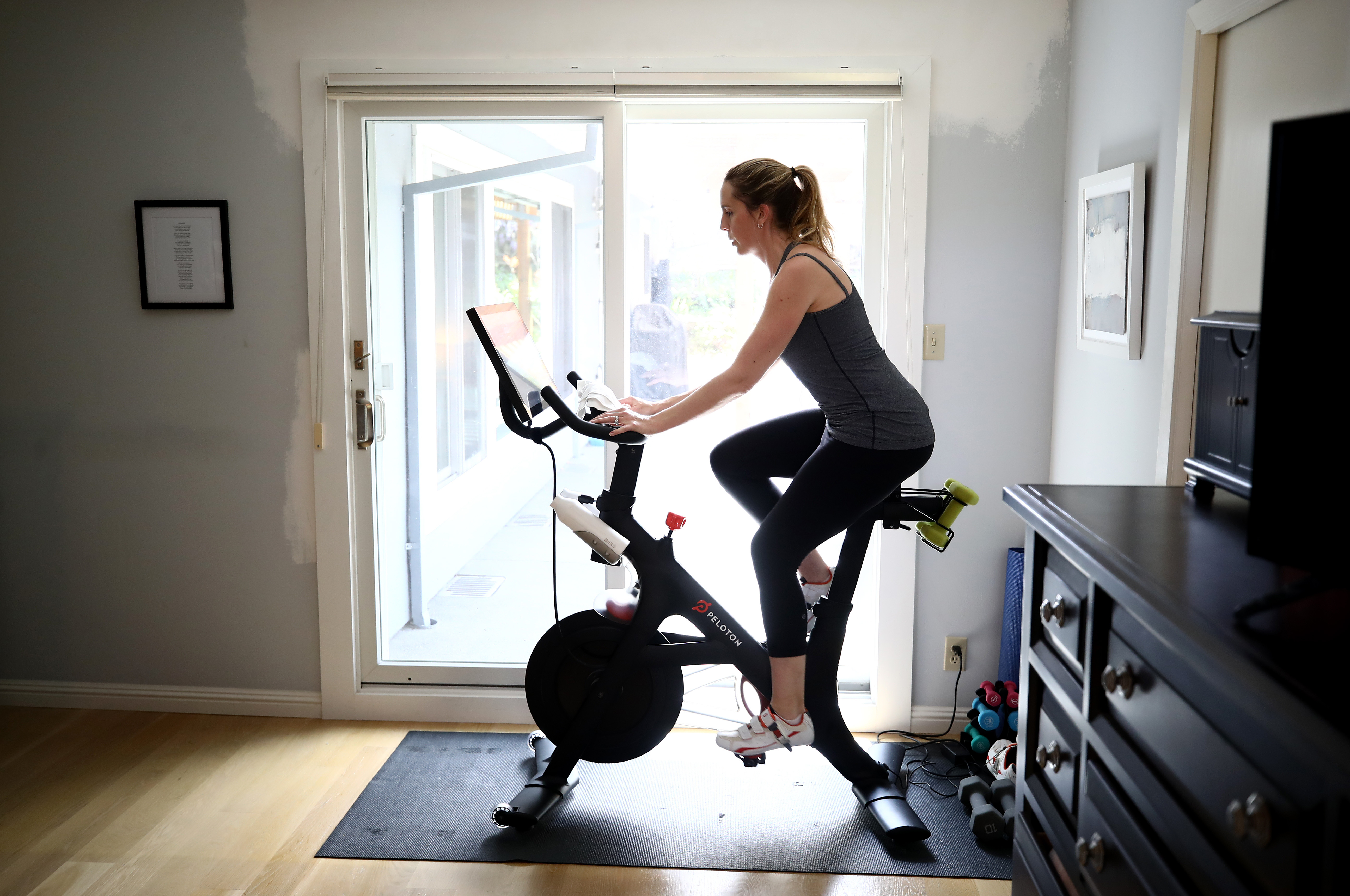 SAN ANSELMO, CALIFORNIA - APRIL 07: Jen Van Santvoord rides her Peloton exercise bike at her home on April 07, 2020 in San Anselmo, California. More people are turning to Peloton due shelter-in-place orders because of the coronavirus (COVID-19). The Peloton stock has continued to rise over recent weeks even as most of the stock market has plummeted. Peloton announced yesterday that they will temporarily pause all live classes until the end of April because an employee tested positive for COVID-19. (Photo by Ezra Shaw/Getty Images)
