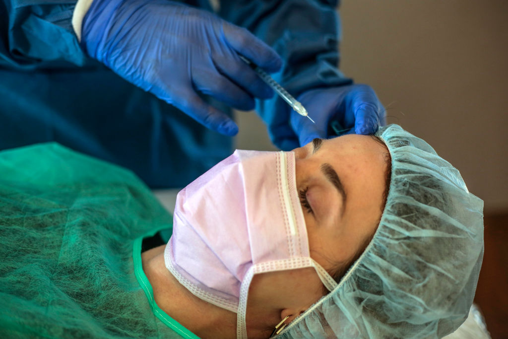 A patient receives a botox treatment wearing PPE kit as part of the new protocols for action and protection against the COVID 19 pandemic for clients during the demonstration for the photographer at IM Ivan Manero Aesthetic Surgery Clinic on May 11, 2020 in Sant Cugat, Spain.