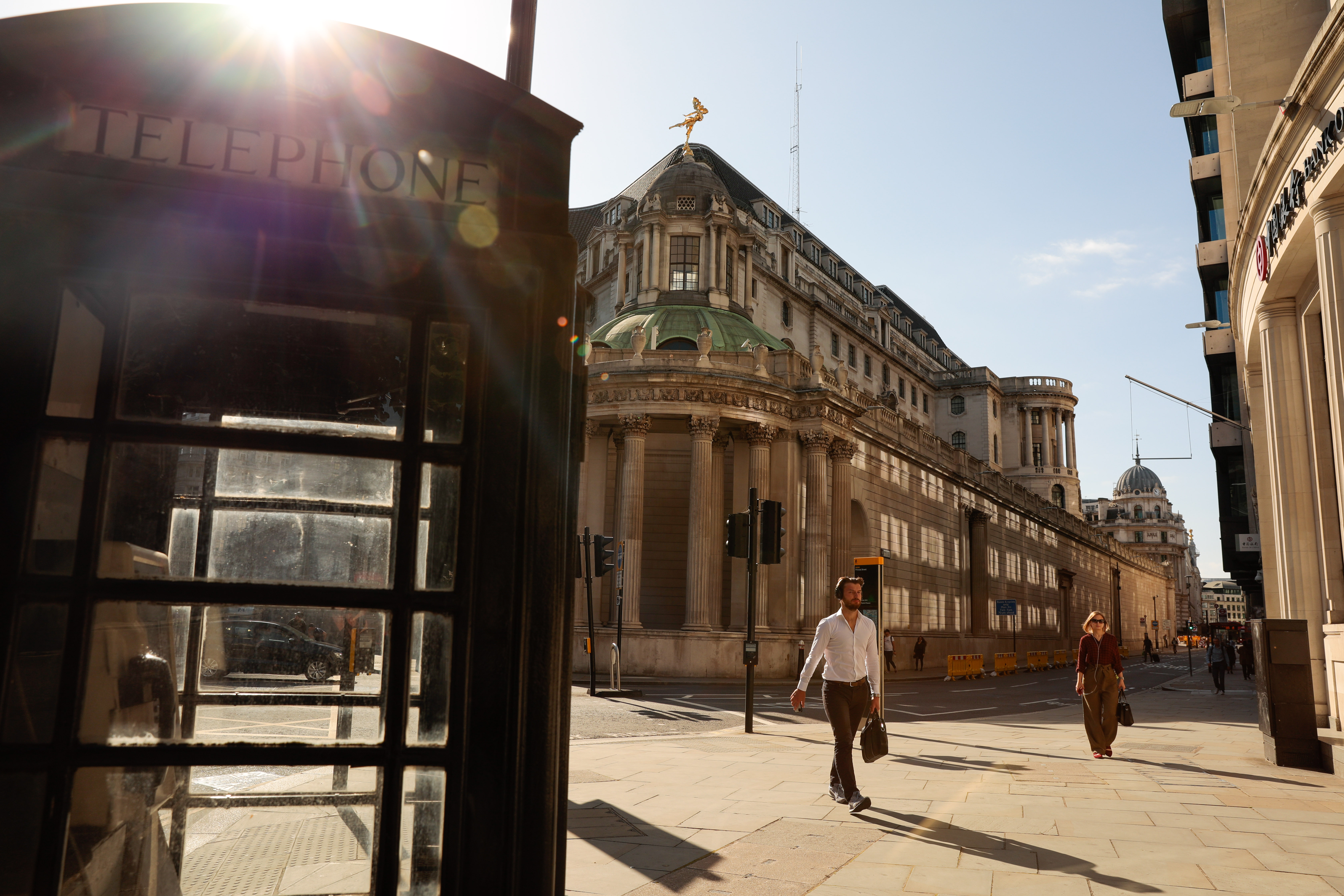 Commuters walk along a street towards a traditional red telephone box in view of the Bank of England (BOE) in the City of London, U.K., on Monday, July 20, 2020. U.K. Prime Minister Boris Johnson nudged Britons back to their office desks in an effort to revive the U.K.'s coronavirus-battered economy that risks putting him at odds with his own top scientific adviser. Photographer: Jason Alden/Bloomberg via Getty Images