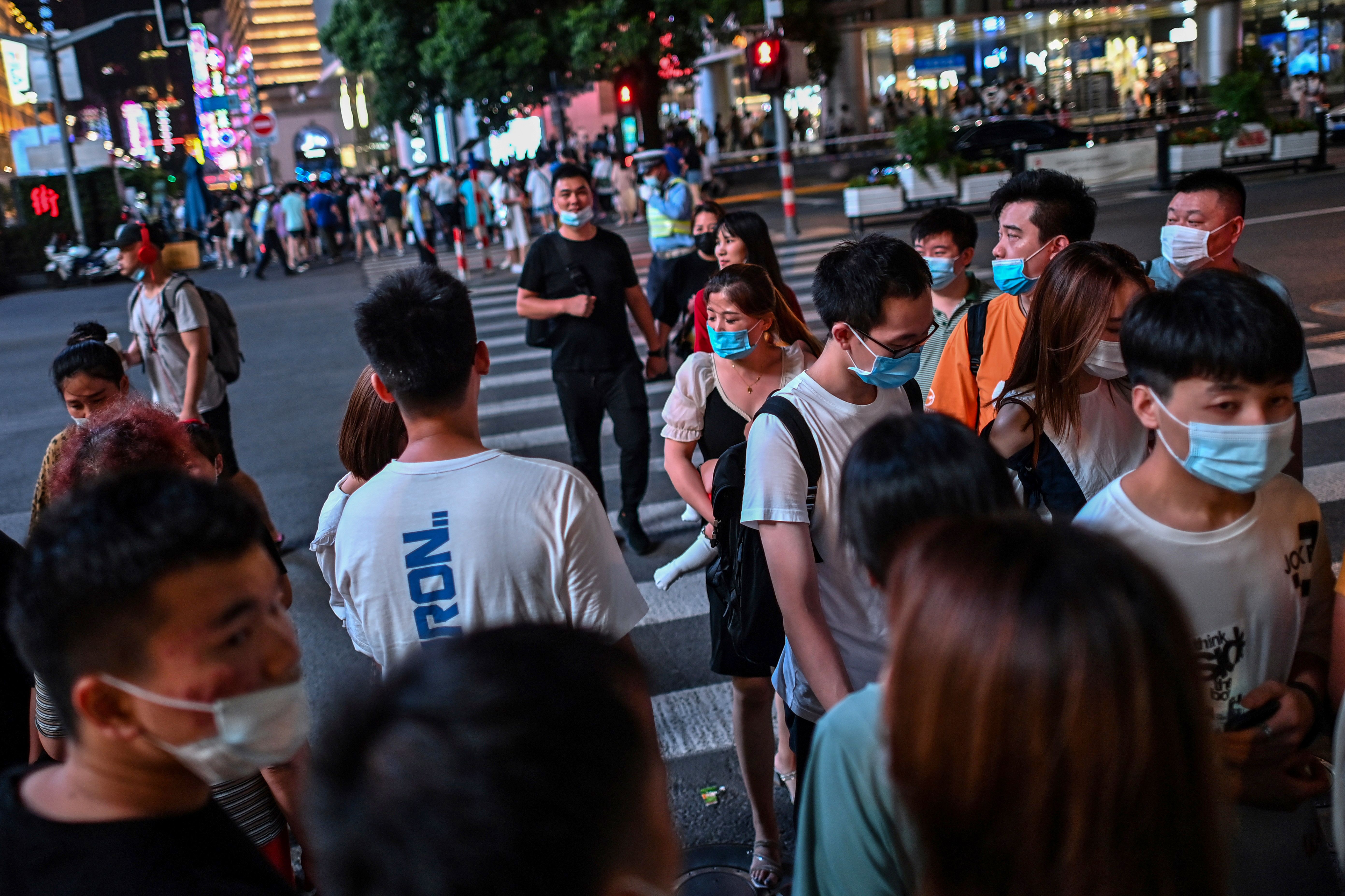 People walk along a street surrounded by shops and malls in Shanghai on July 31, 2020. (Photo by Hector RETAMAL / AFP) (Photo by HECTOR RETAMAL/AFP via Getty Images)