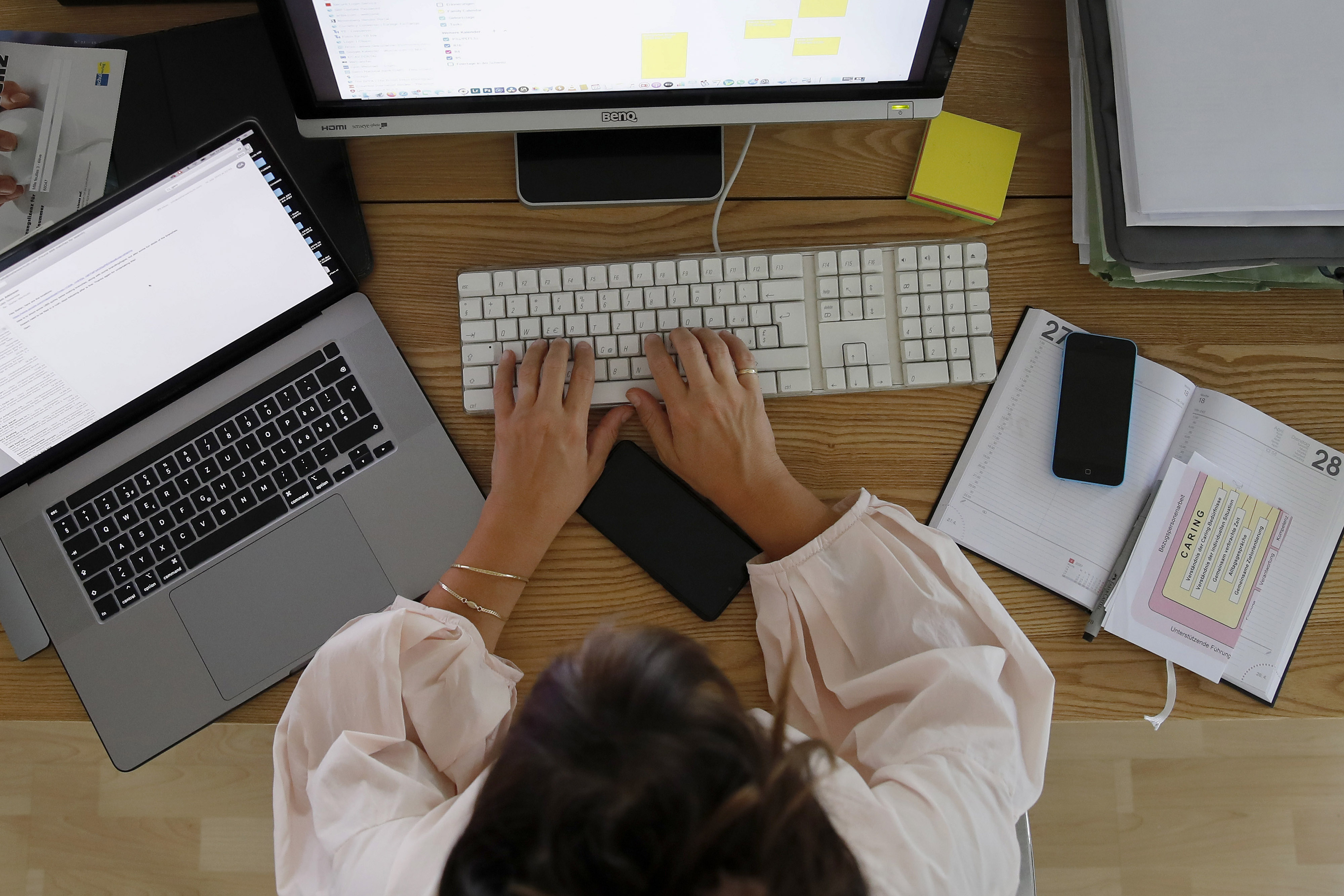 A woman works at a desktop computer alongside an Apple Inc. laptop in a home office in this arranged photograph taken in Bern, Switzerland, on Saturday, Aug. 22, 2020.