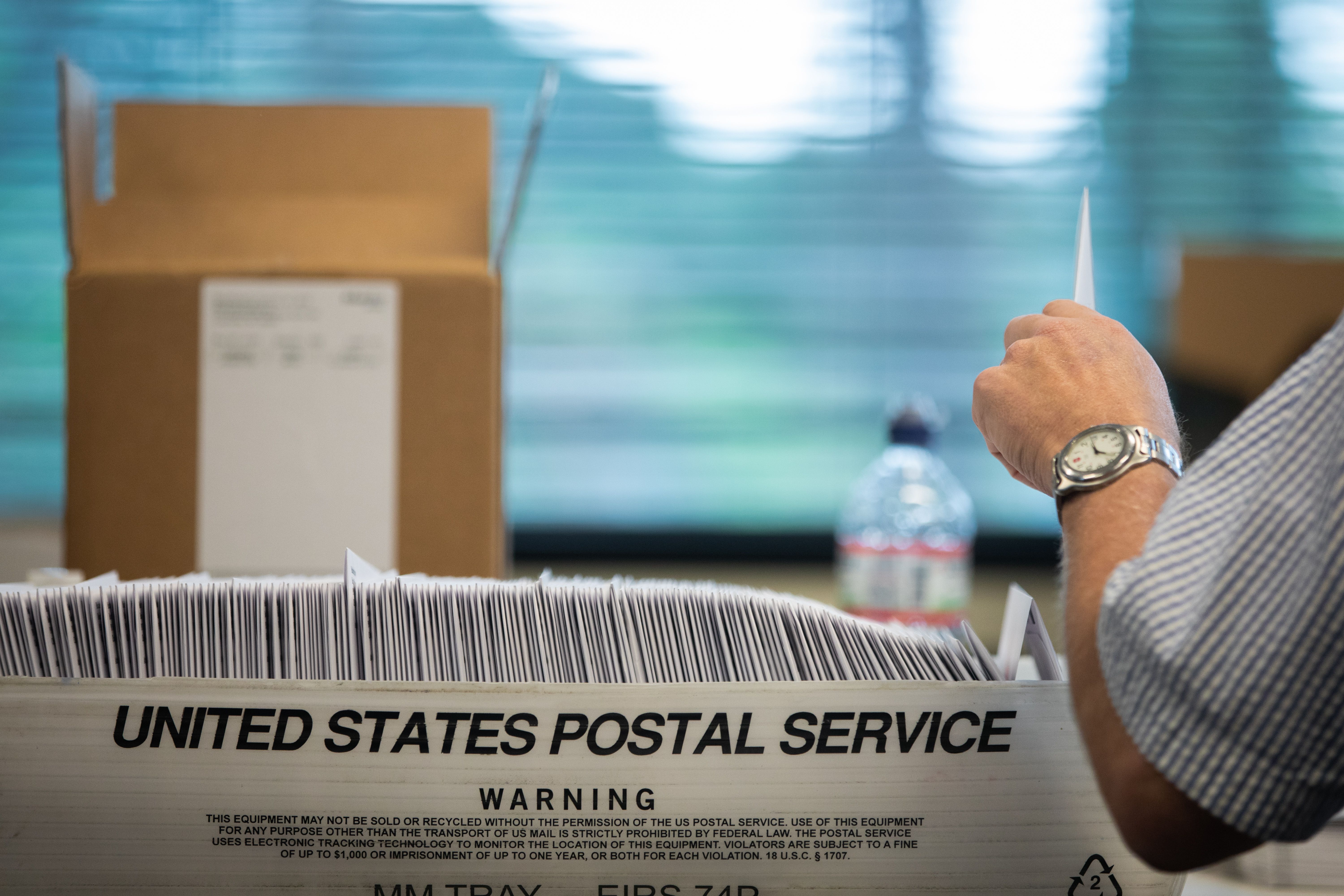 An election worker stuffs ballot applications at the Mecklenburg County Board of Elections office in Charlotte, N.C. "Some of the most widely circulated concerns surrounding mail-in voting fraud are not grounded in fact," the authors write.   (Photo by LOGAN CYRUS/AFP via Getty Images)