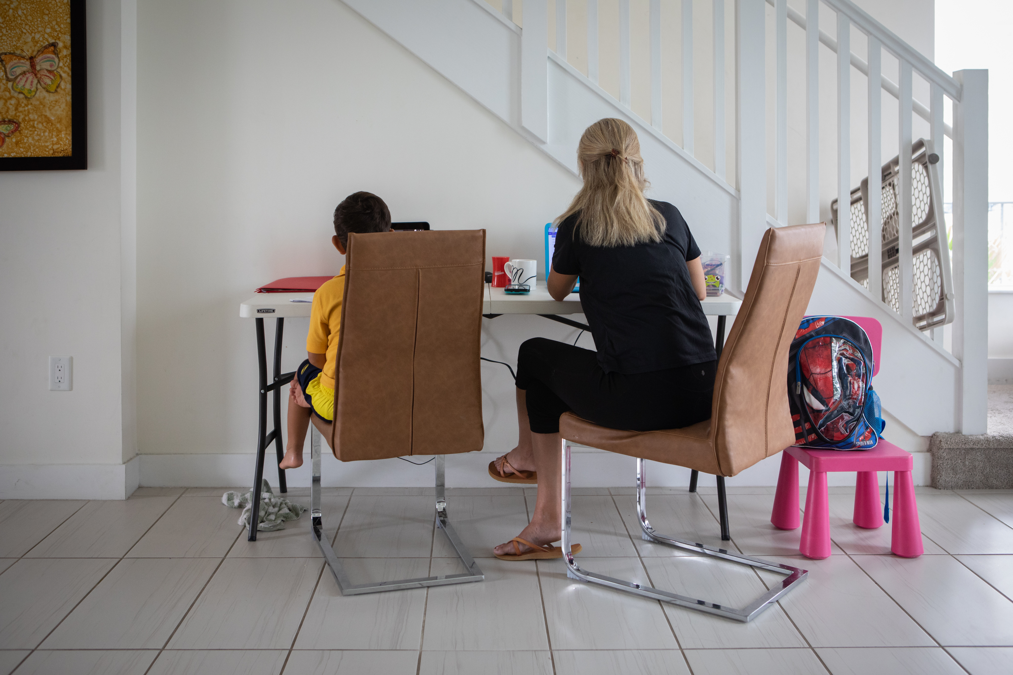 A mother works from home while her son attends school remotely in an arranged photograph taken in Miami, Florida, U.S., on Tuesday, Sept. 8, 2020. Tens of thousands of students and teachers haven't been able to access K12's My School Online platform this week. Miami-Dade public school revealed Wednesday that the district never signed a $15.3m no-bid contract with K12 Inc., the company at the center of the "unprecedented crisis," according to a Miami Herald report. Jayme Gershen/Bloomberg via Getty Images